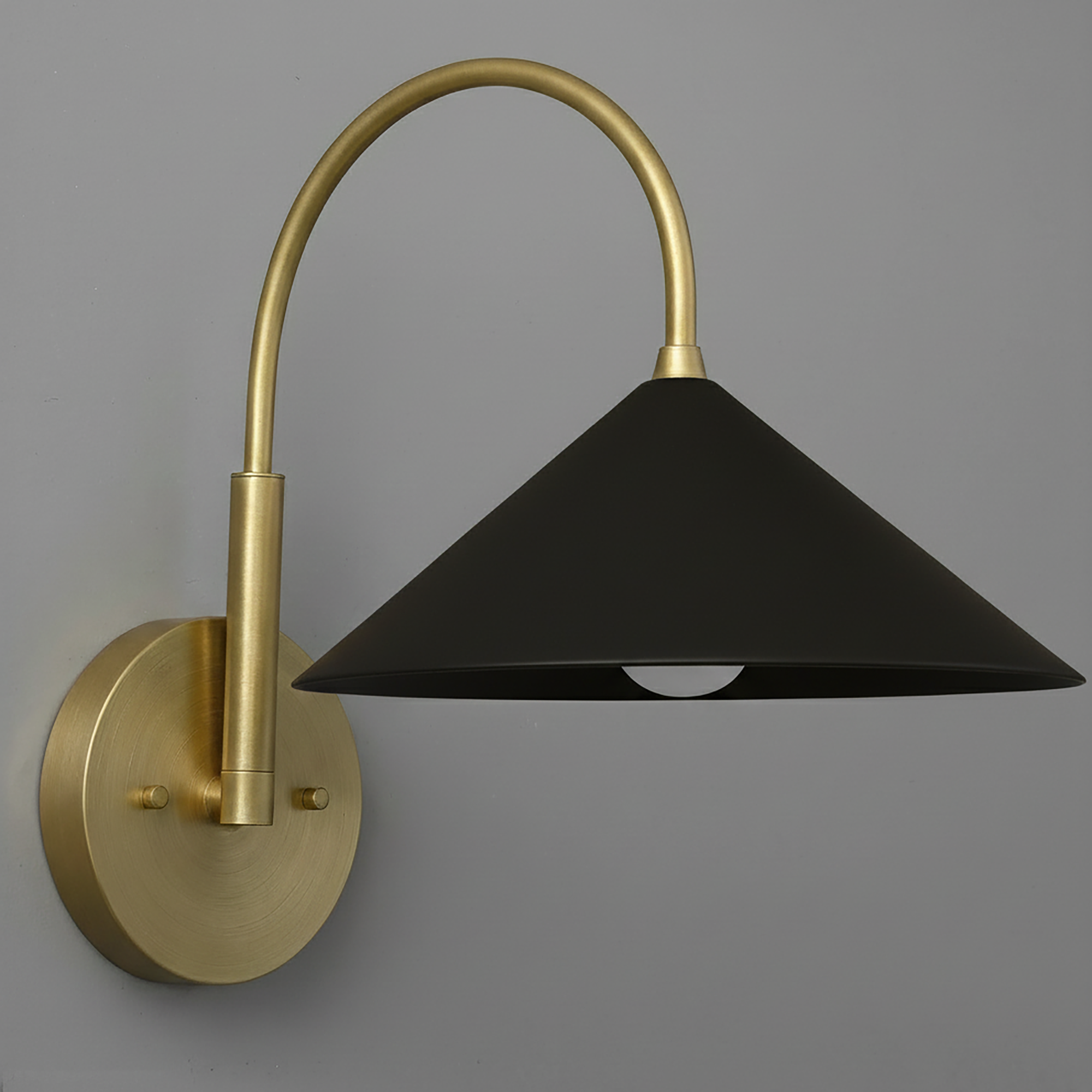 Antique brass sconce with curved arm and matte black conical shade mounted on round backplate. - Sconce Model No. 1583