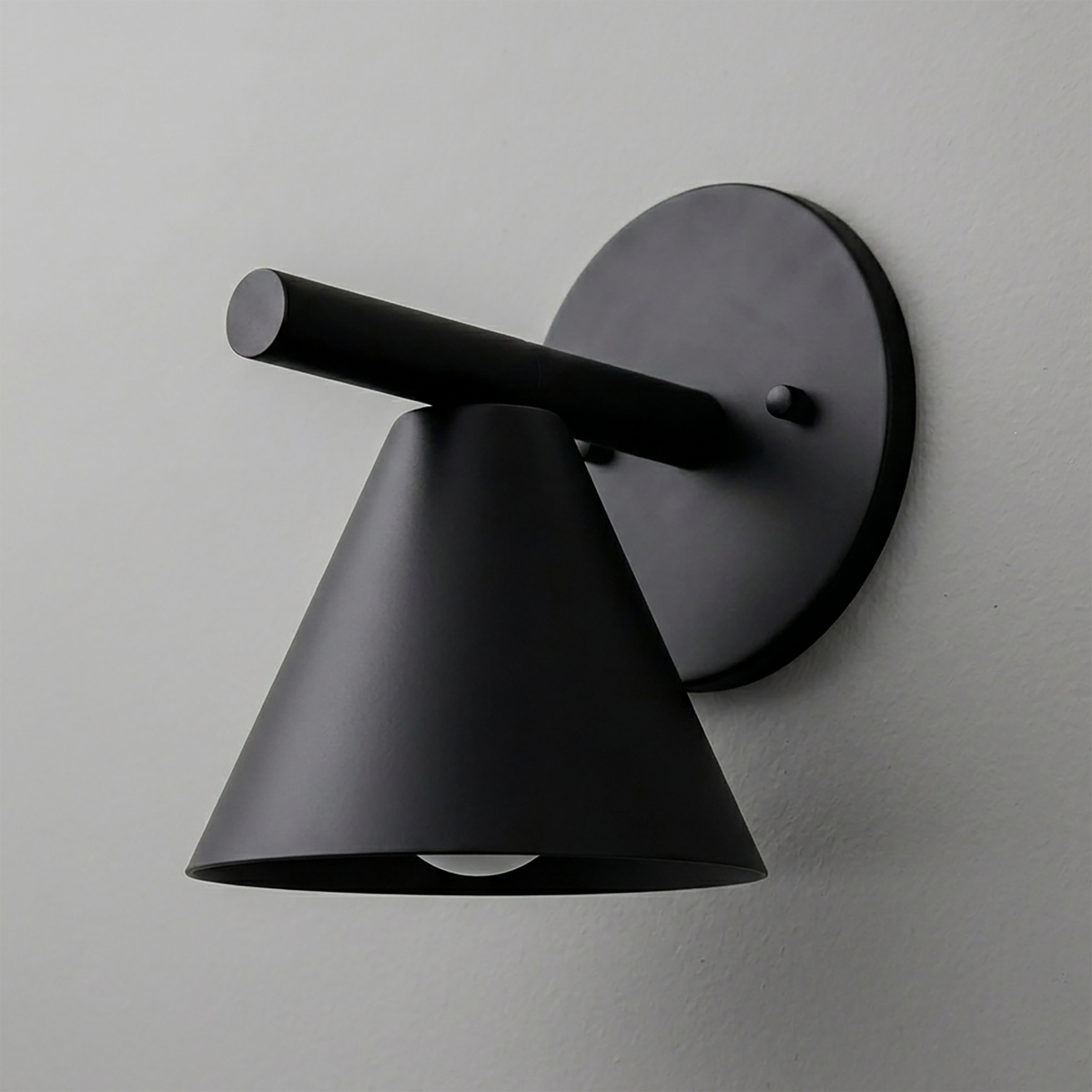 Matte black metal wall sconce with conical shade and cylindrical arm mounted on round backplate. - SCONCE MODEL NO. 5075