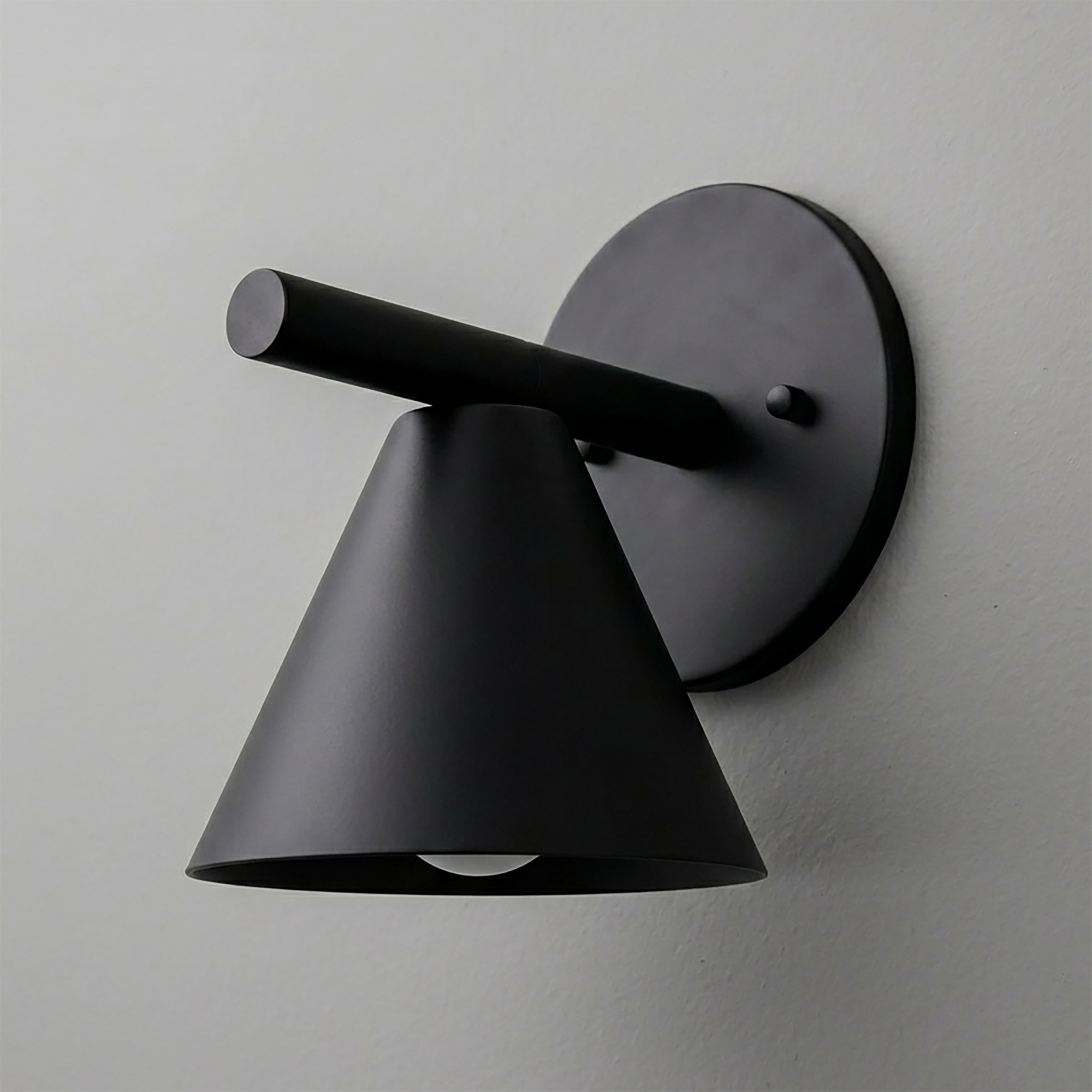 Matte black metal wall sconce with conical shade and cylindrical arm mounted on round backplate. - SCONCE MODEL NO. 5075