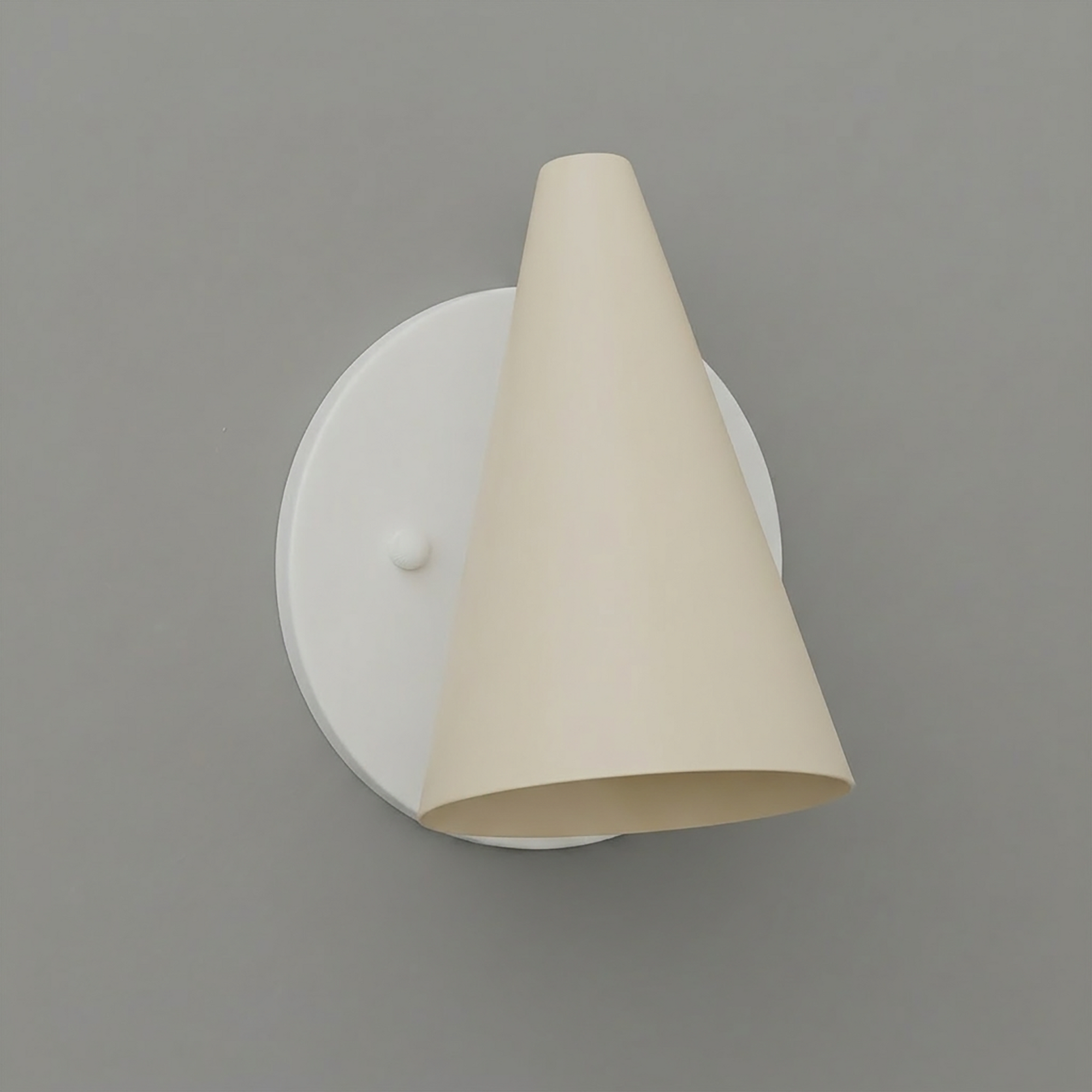 Modern wall sconce with matte white circular base and angled cream-colored conical shade. - SCONCE MODEL NO. 5950
