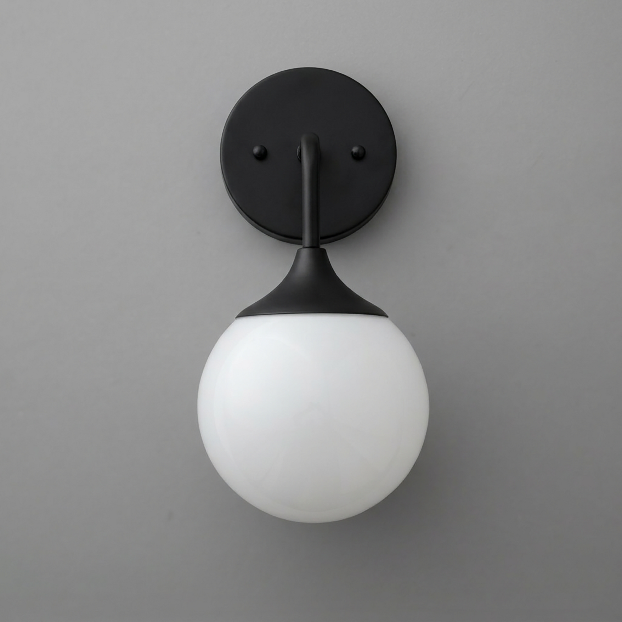 Black metal wall sconce with a round backplate and white frosted glass globe shade. - SCONCE MODEL NO. 1752