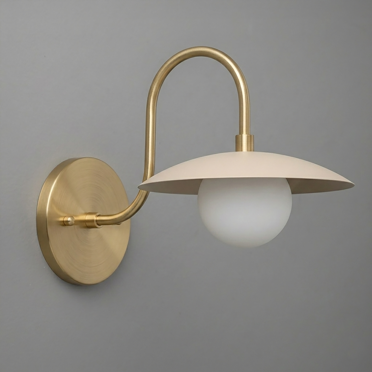 Brushed brass wall sconce with curved arm, flat dome shade, and white globe bulb. - SCONCE MODEL NO. 3799