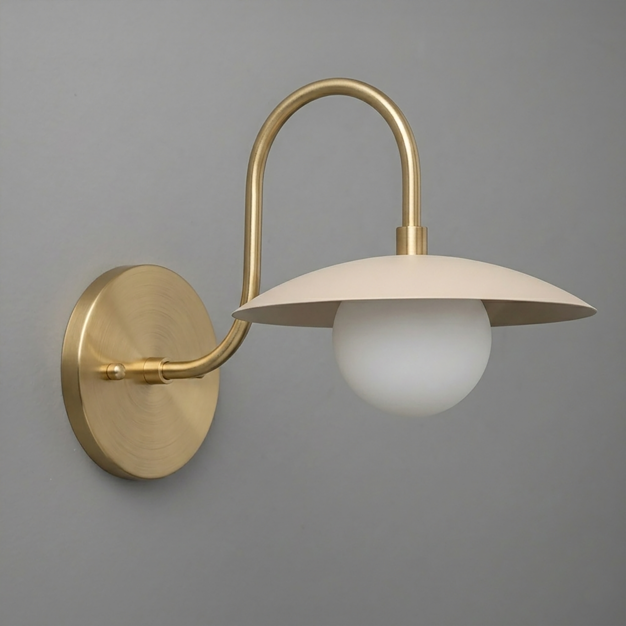 Brushed brass wall sconce with curved arm, flat dome shade, and white globe bulb. - SCONCE MODEL NO. 3799