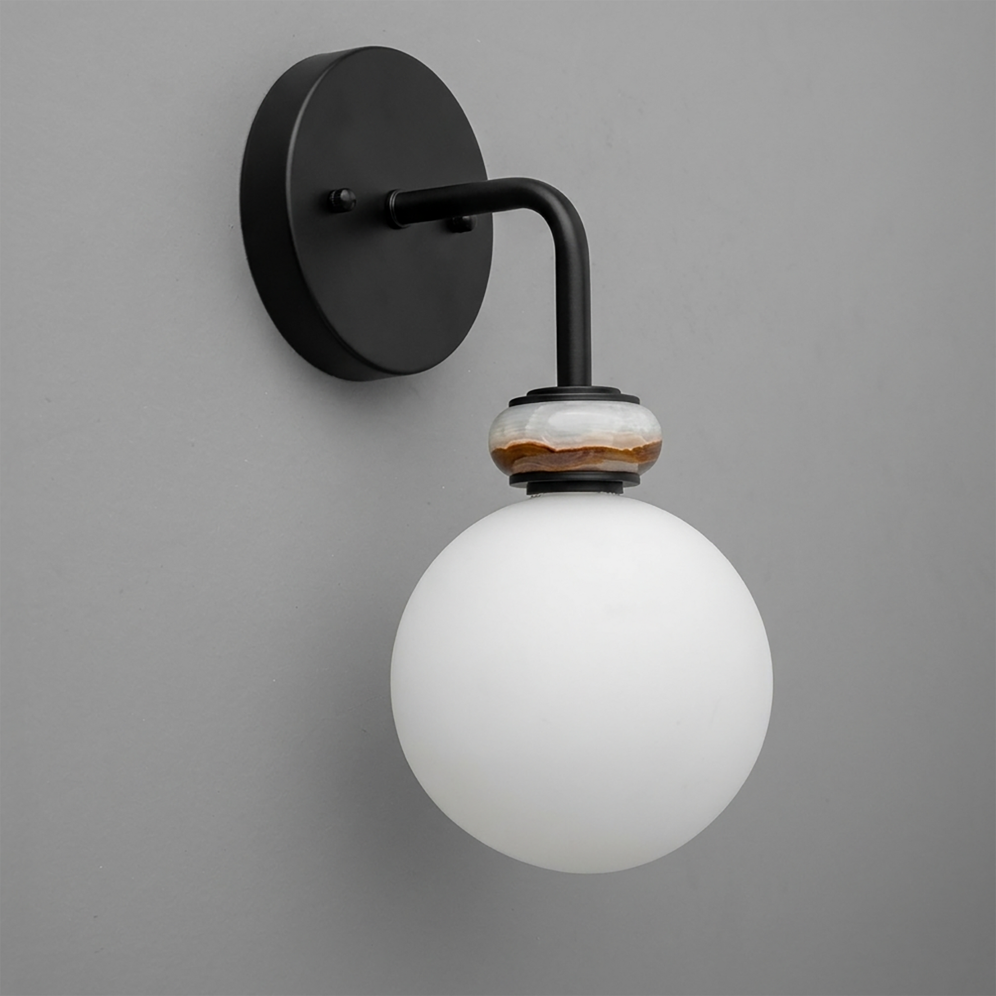 Black metal wall sconce with a white frosted glass globe and a decorative amber ring near the bulb socket. - SCONCE MODEL NO. 5449