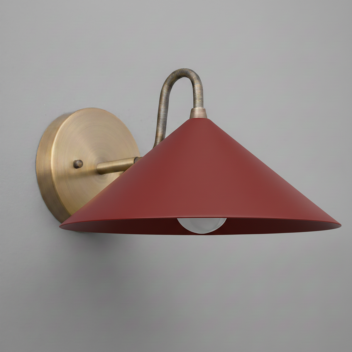 Wall sconce with antique brass mount and curved arm, featuring a wide brick red conical shade. - SCONCE MODEL NO. 6528