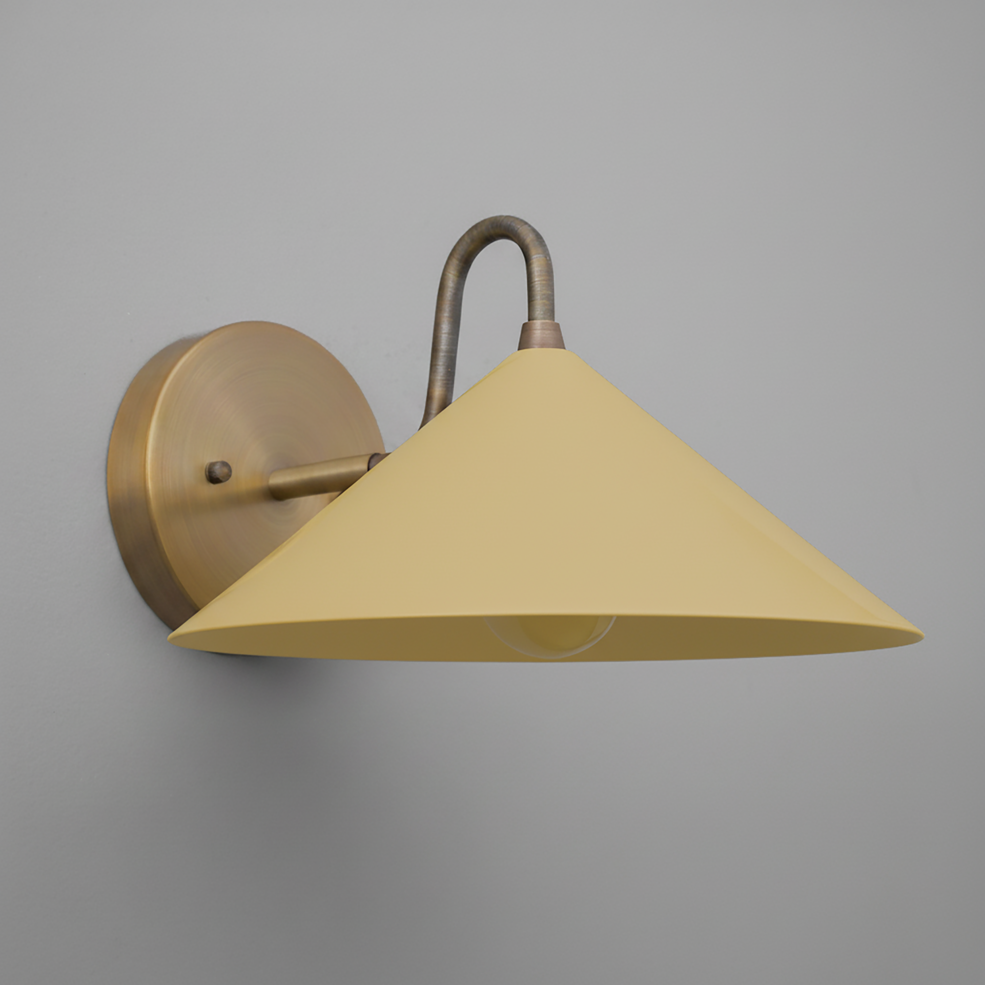 Wall sconce with antique brass round base and curved arm, yellow conical metal shade. - SCONCE MODEL NO. 6528