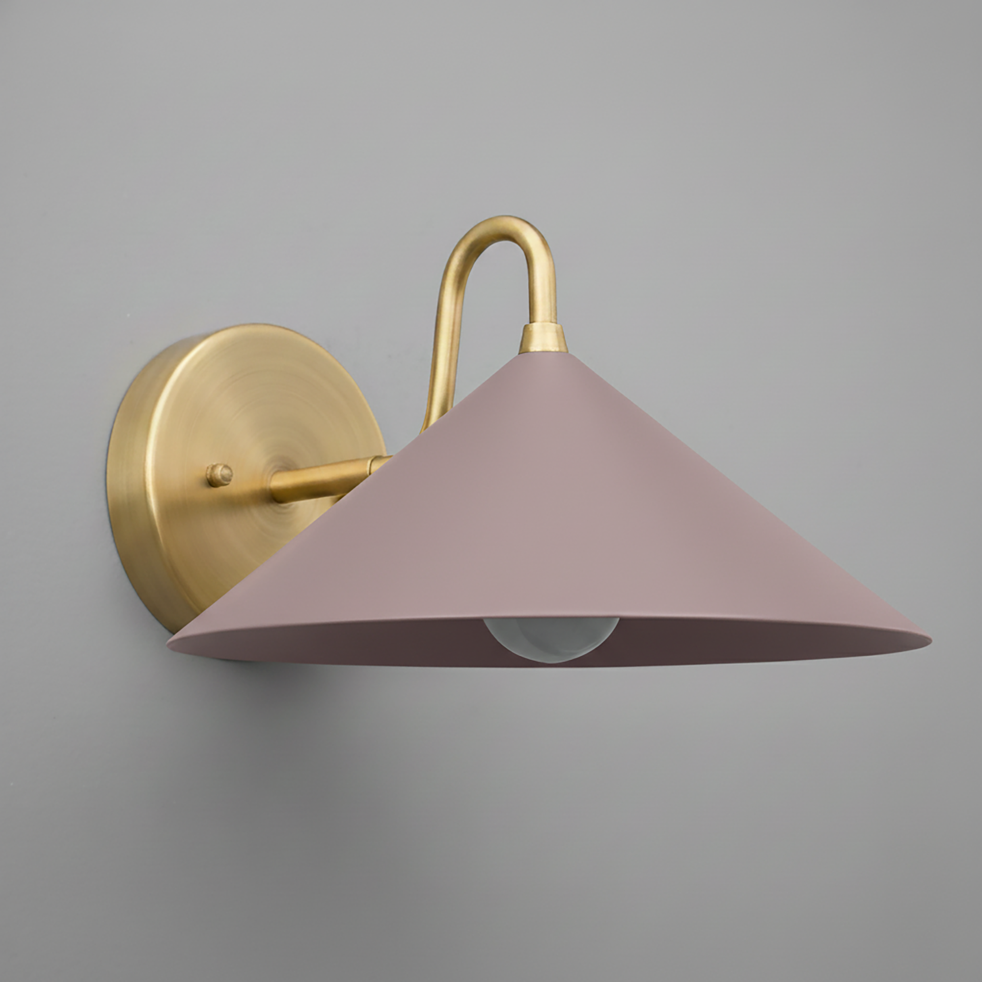 Wall sconce with antique brass finish and mauve conical metal shade mounted on gray wall. - SCONCE MODEL NO. 6528