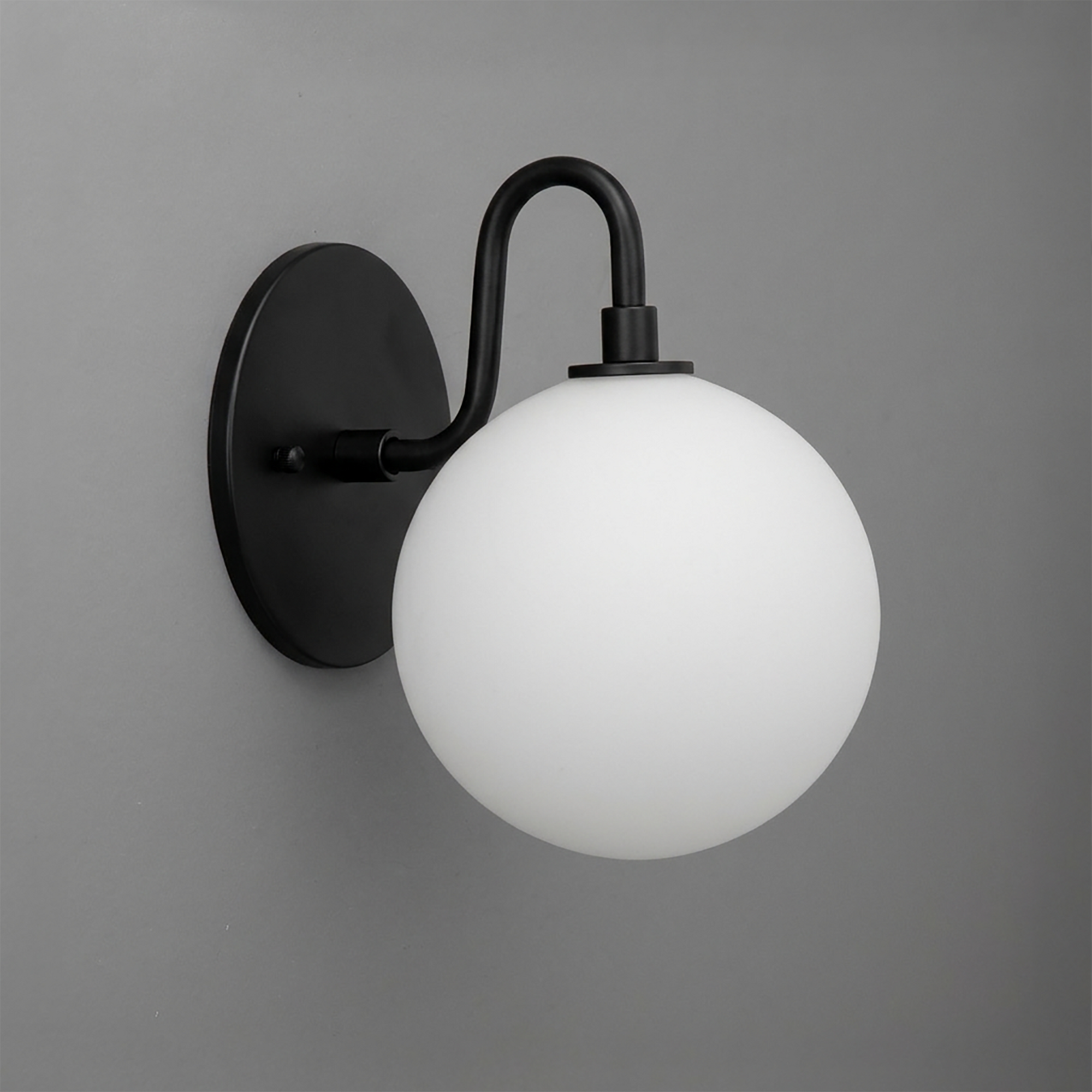 Black metal wall sconce with a smooth curved arm holding a frosted white glass globe shade. - SCONCE MODEL NO. 8637