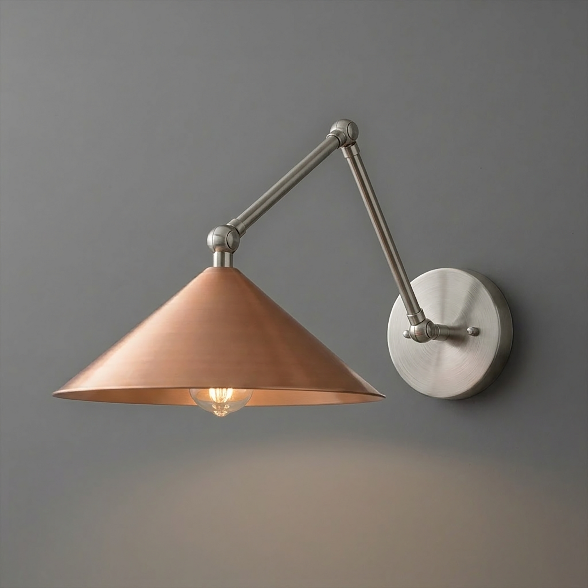 Wall-mounted sconce with brushed metal arm and round base, featuring a wide copper cone shade and two exposed bulbs. - SCONCE MODEL NO. 6414
