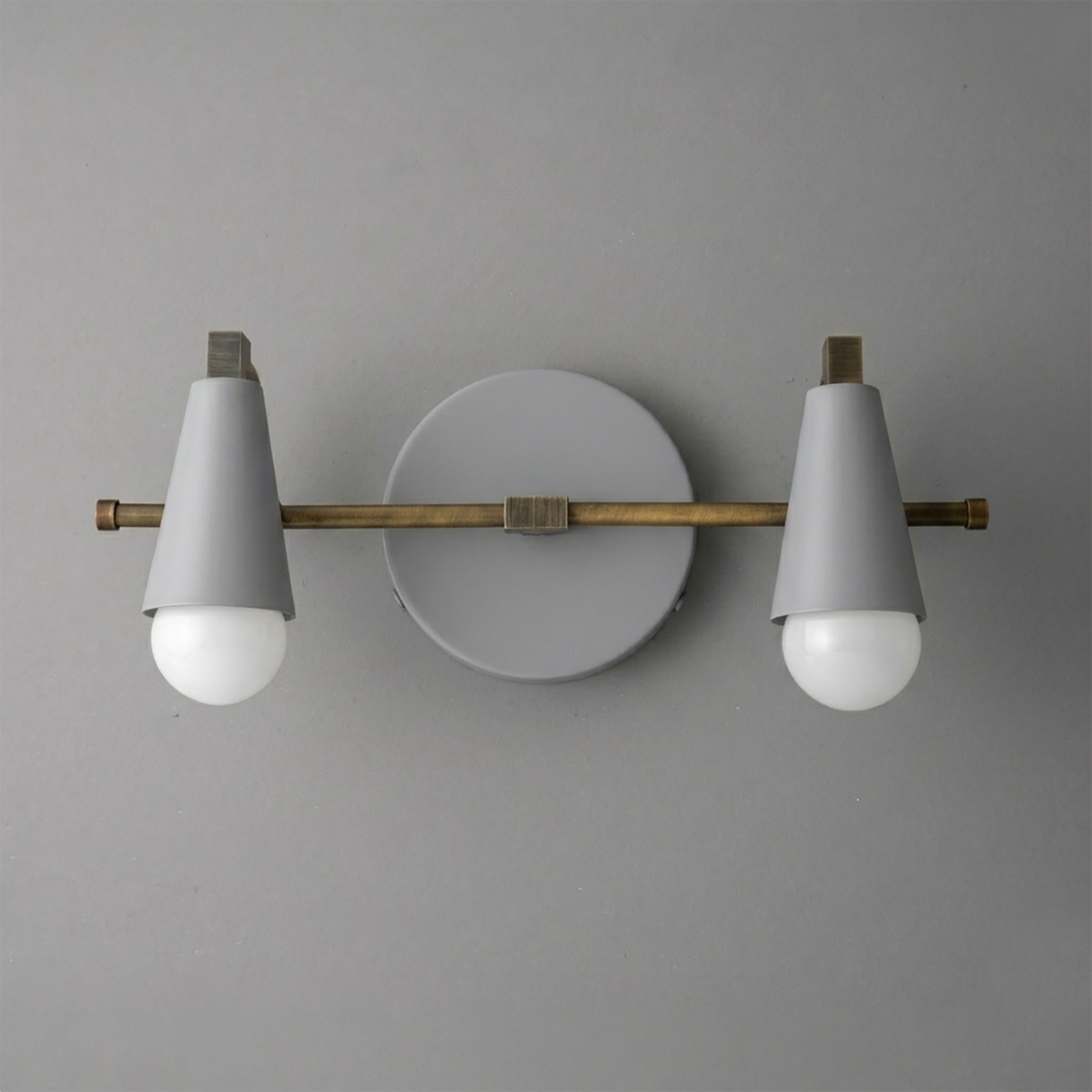 Scandinavian style vanity light with white cone shades, two exposed bulbs, brass horizontal rod, and round white wall mount. - VANITY LIGHT MODEL NO. 1229