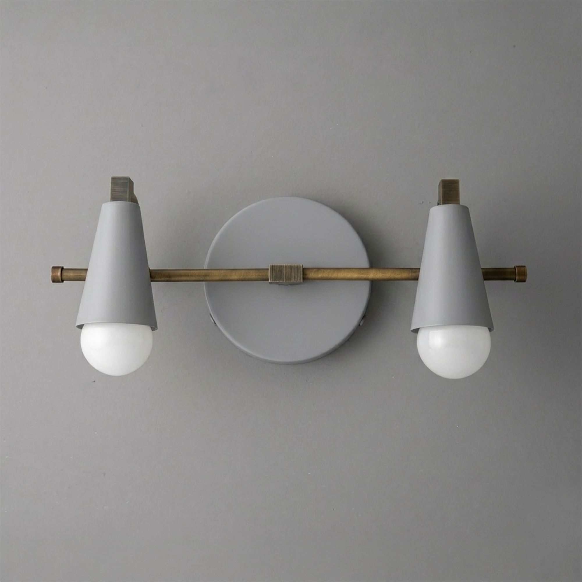 Scandinavian style vanity light with white cone shades, two exposed bulbs, brass horizontal rod, and round white wall mount. - VANITY LIGHT MODEL NO. 1229