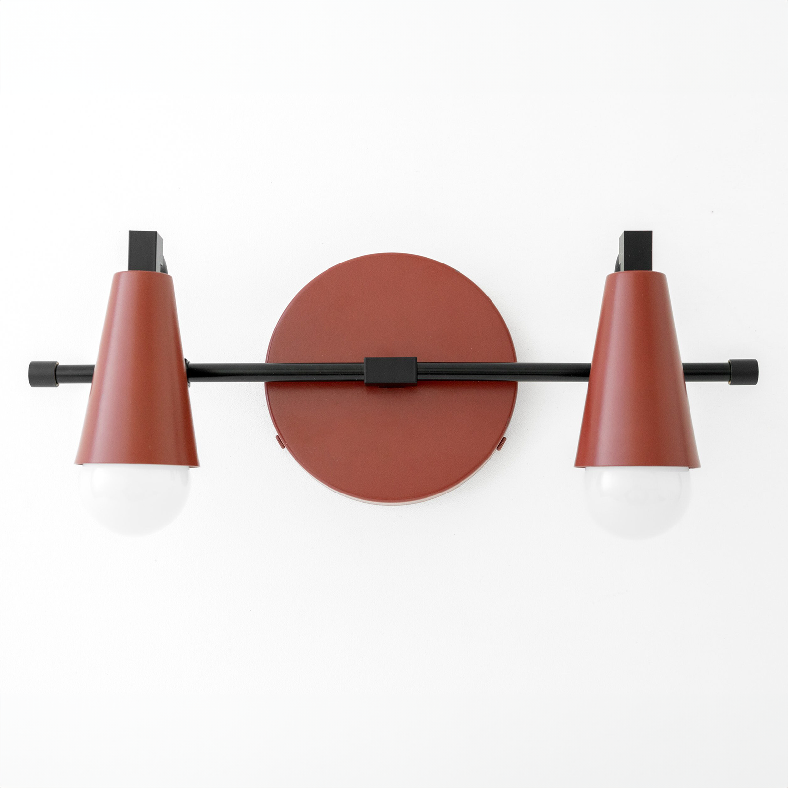 Industrial-style vanity light with two cone-shaped rust-colored shades and exposed white bulbs on a black horizontal bar. - VANITY LIGHT MODEL NO. 1229