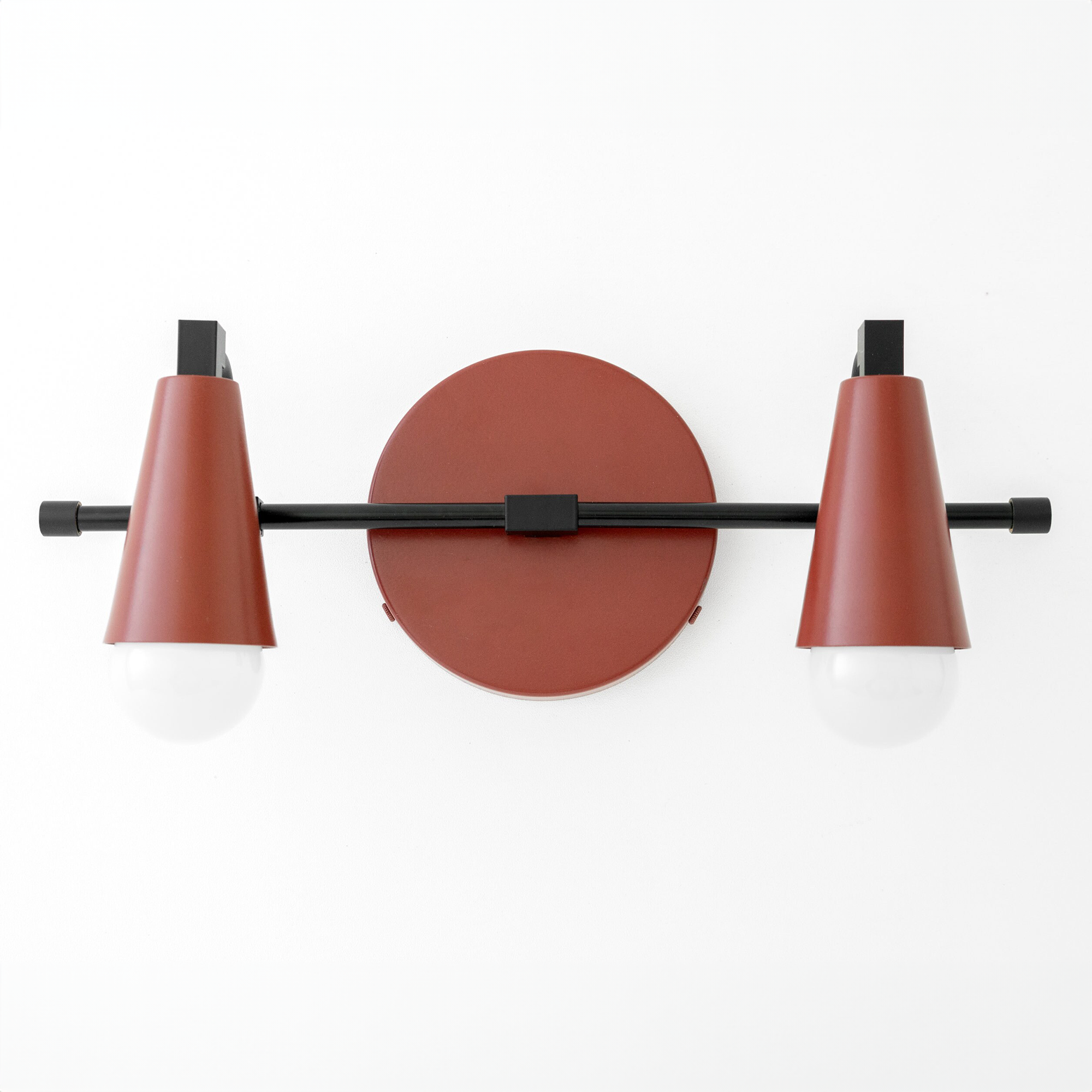 Industrial-style vanity light with two cone-shaped rust-colored shades and exposed white bulbs on a black horizontal bar. - VANITY LIGHT MODEL NO. 1229