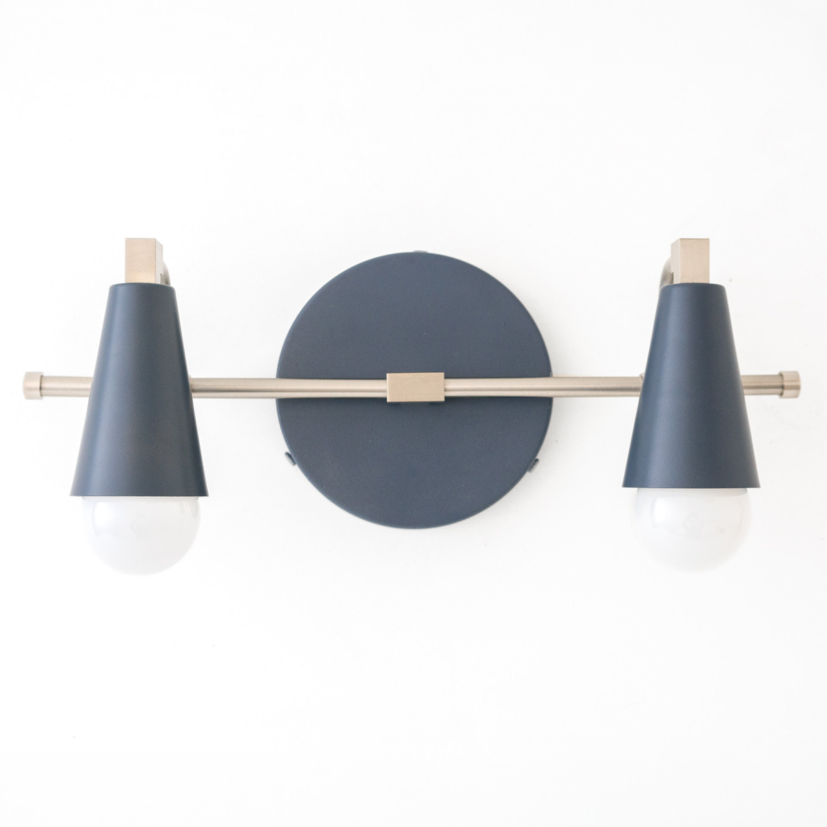 Scandinavian-style vanity light with two exposed round bulbs and matte dark blue conical shades on a brass horizontal bar. - VANITY LIGHT MODEL NO. 1229