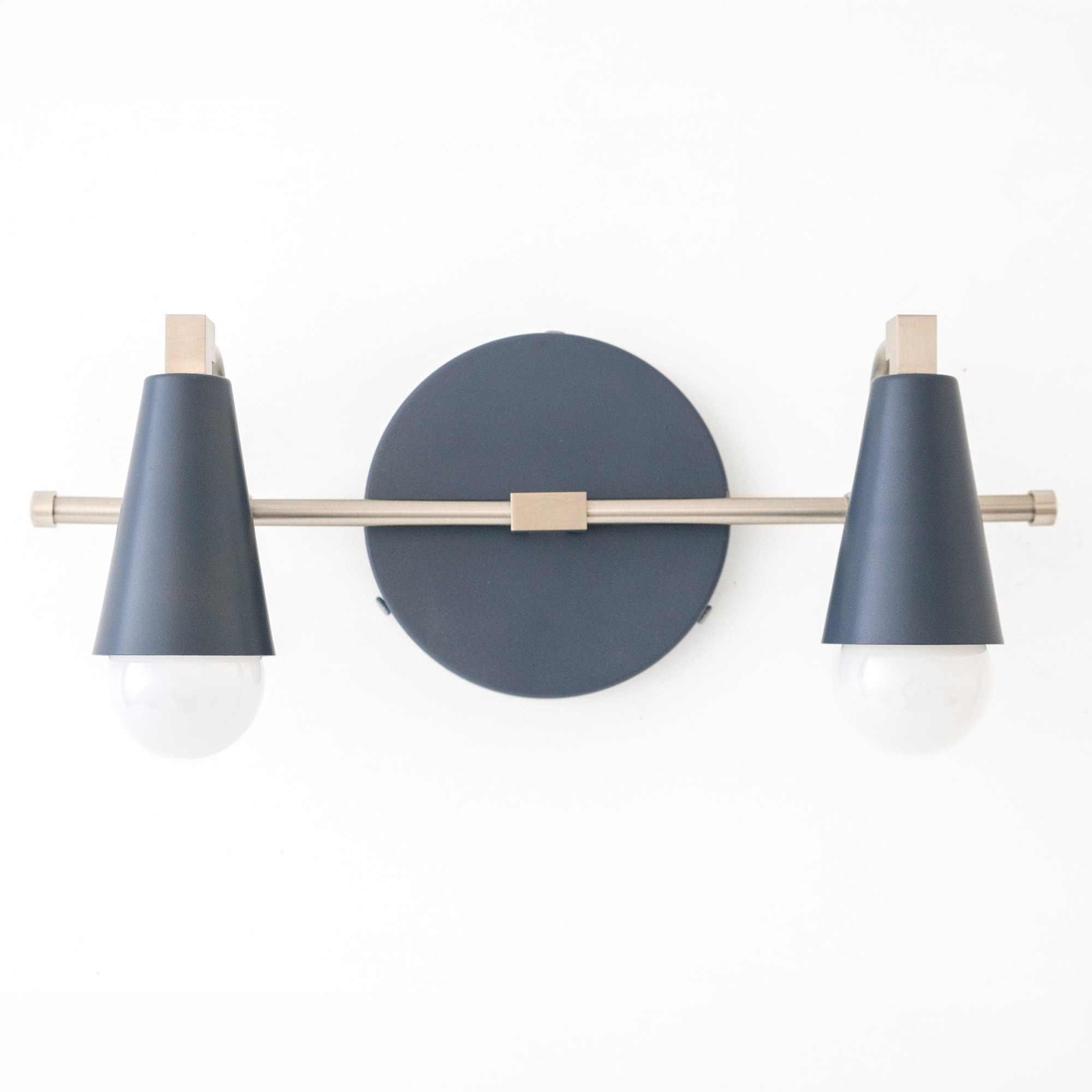 Scandinavian-style vanity light with two exposed round bulbs and matte dark blue conical shades on a brass horizontal bar. - VANITY LIGHT MODEL NO. 1229