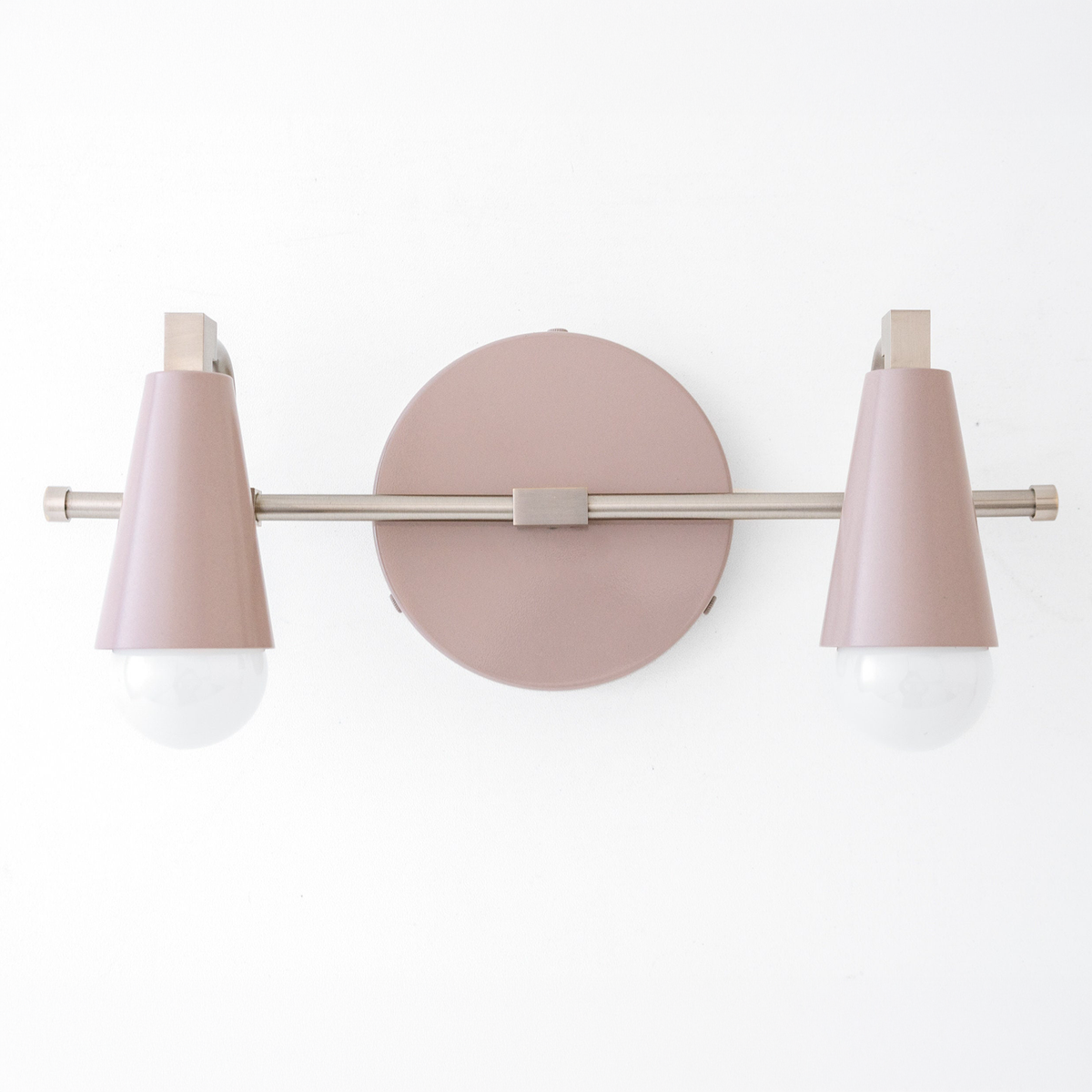 Scandinavian-style vanity light with two pink cone-shaped shades and exposed bulbs on a matte metal bar and round base. - VANITY LIGHT MODEL NO. 1229