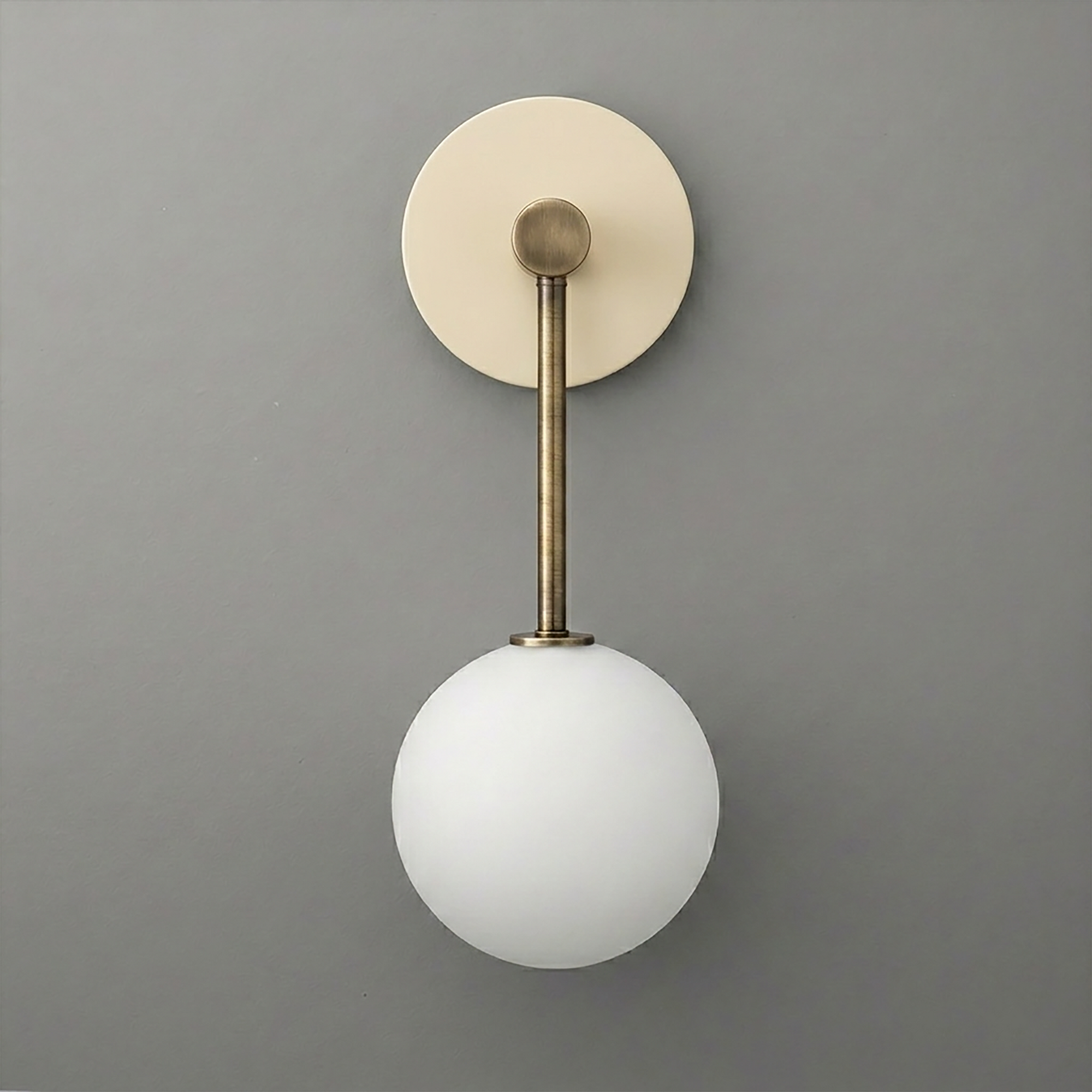 Wall-mounted sconce with aged brass finish and a single frosted white globe light shade. - Sconce Model No. 5999