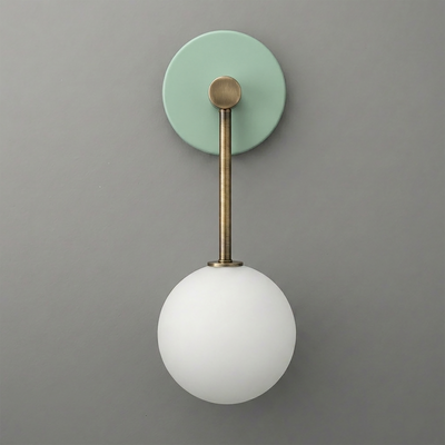 Wall sconce with matte brass rod and green circular backplate, featuring a frosted white glass globe shade. - Sconce Model No. 5999