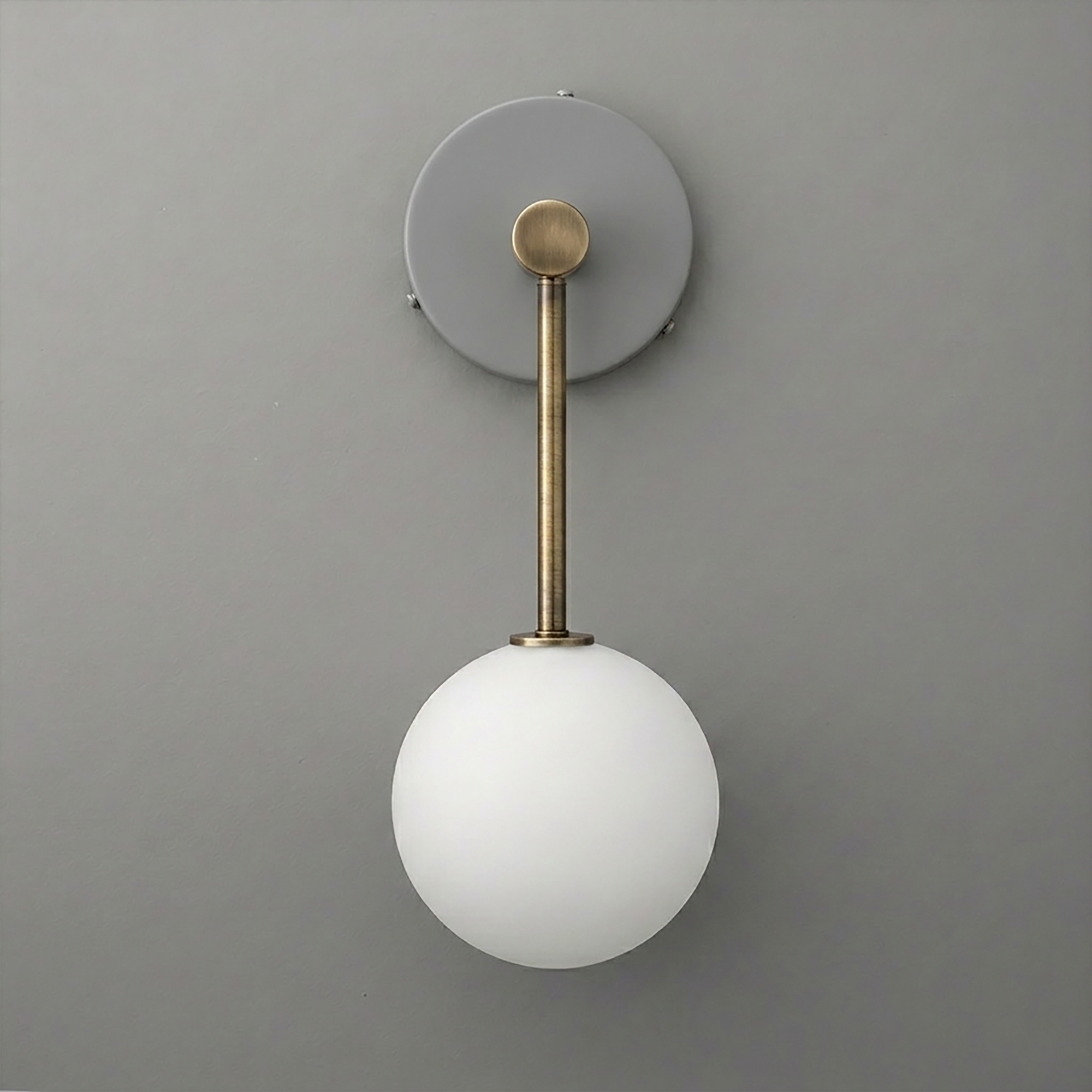 Wall sconce with matte brass rod and round white frosted glass globe shade on gray background. - Sconce Model No. 5999