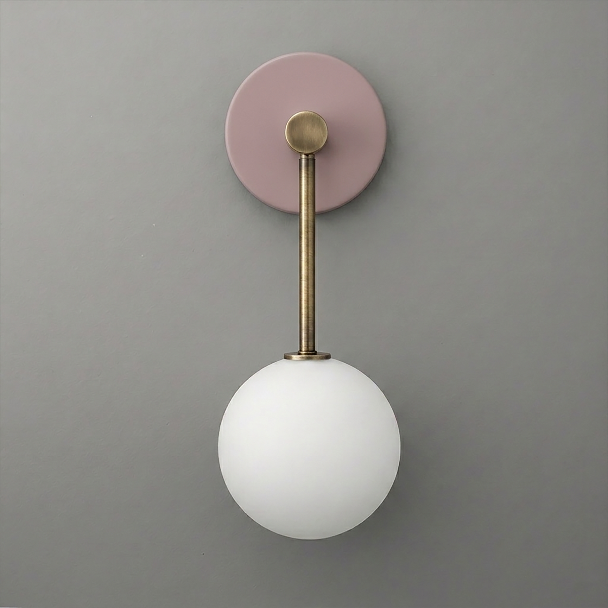 Wall sconce with matte pink circular base, brushed brass rod, and frosted white glass globe light. - Sconce Model No. 5999