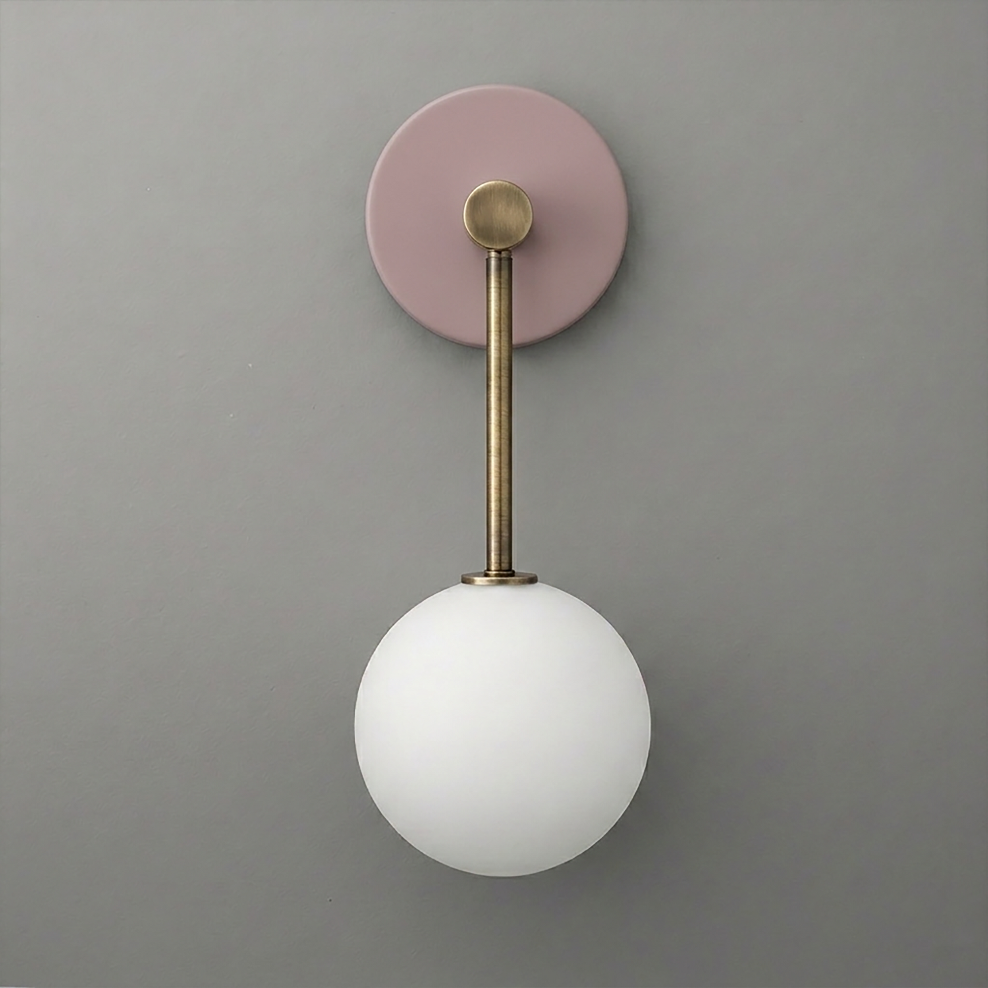 Wall sconce with matte pink circular base, brushed brass rod, and frosted white glass globe light. - Sconce Model No. 5999