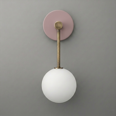 Wall sconce with matte pink circular base, brushed brass rod, and frosted white glass globe light. - Sconce Model No. 5999