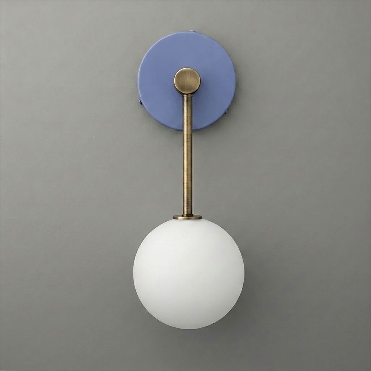 Wall sconce with matte brass rod and round white glass globe on a blue circular backplate. - Sconce Model No. 5999