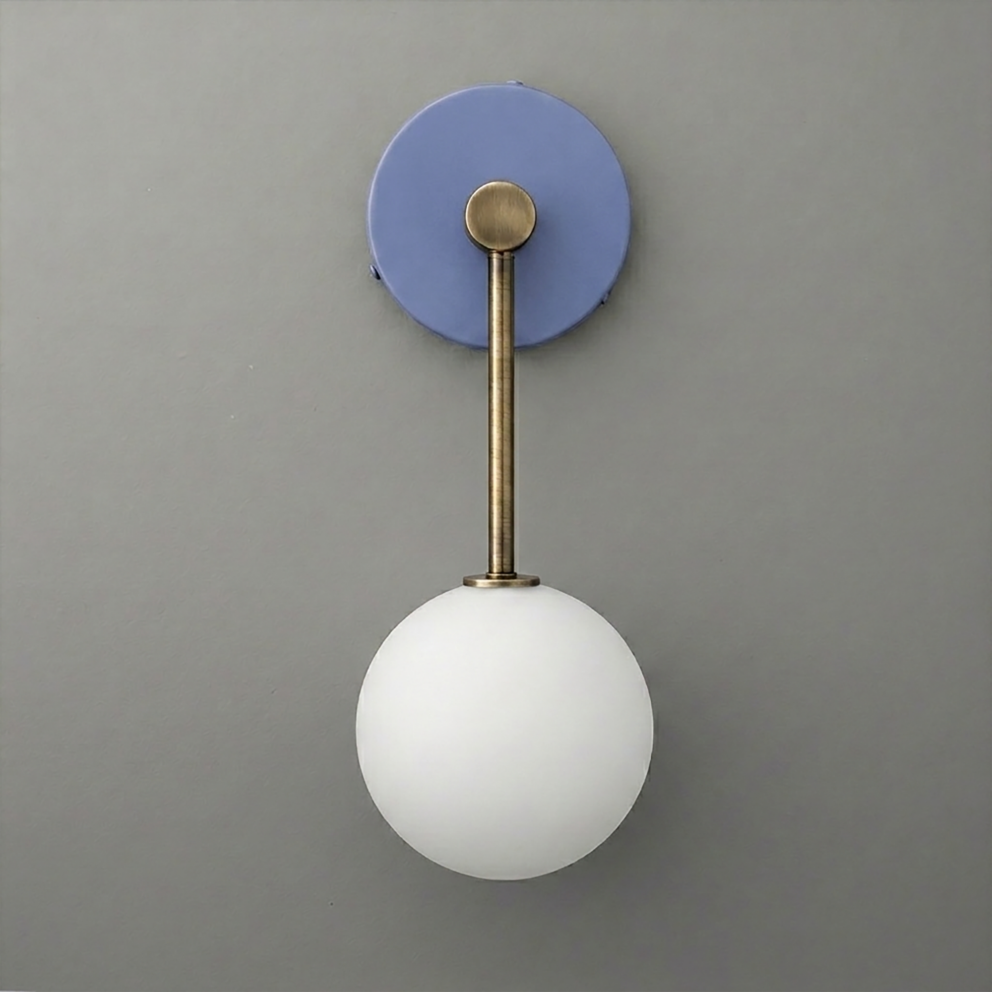 Wall sconce with matte brass rod and round white glass globe on a blue circular backplate. - Sconce Model No. 5999