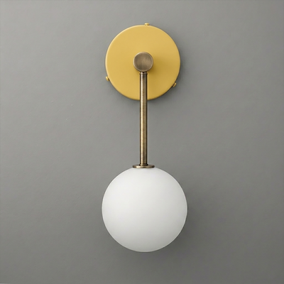 Wall sconce with matte brass fixture and round white frosted glass globe shade on gray background. - Sconce Model No. 5999