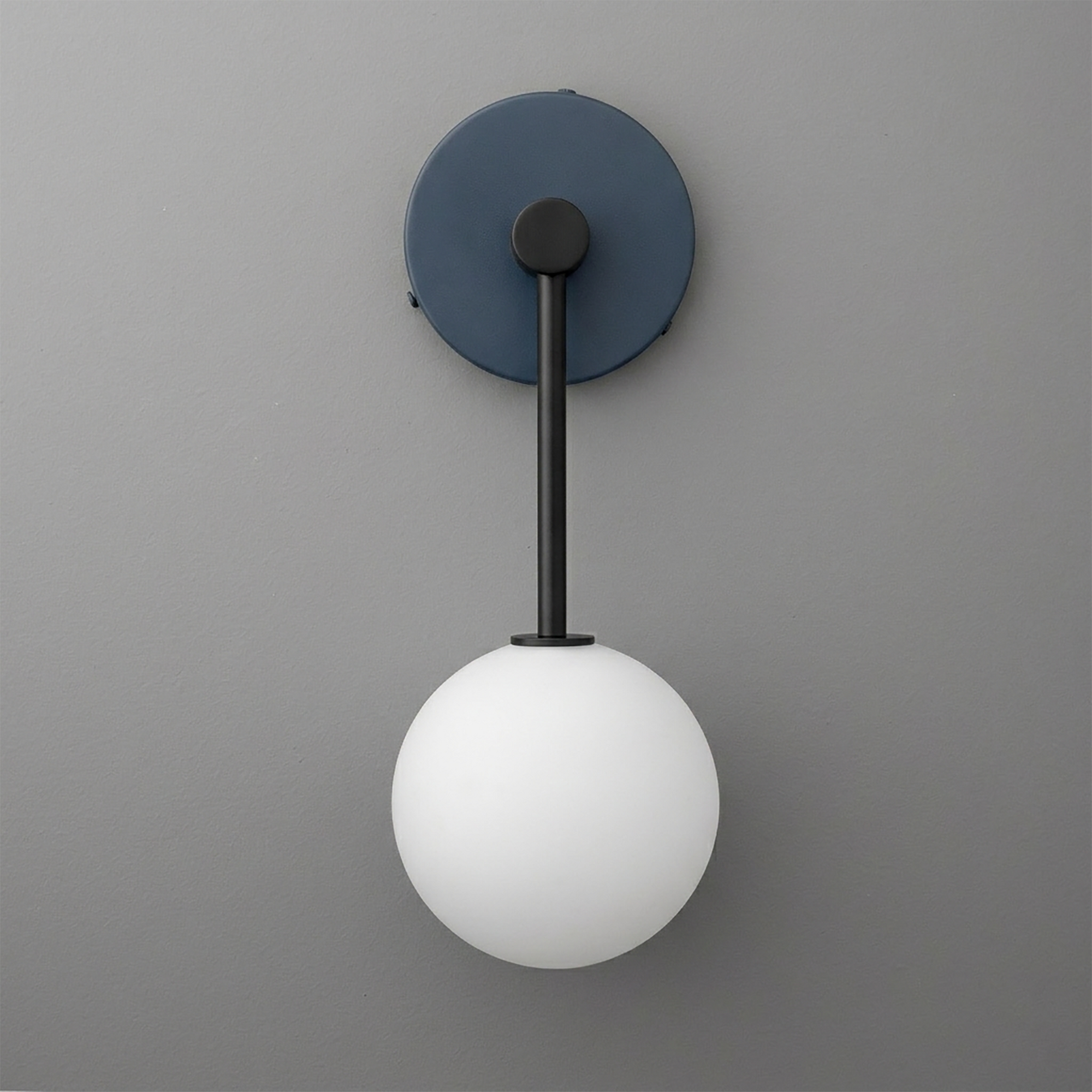 Matte black sconce with a round wall mount and a single white frosted glass globe light hanging from a slim vertical rod. - Sconce Model No. 5999