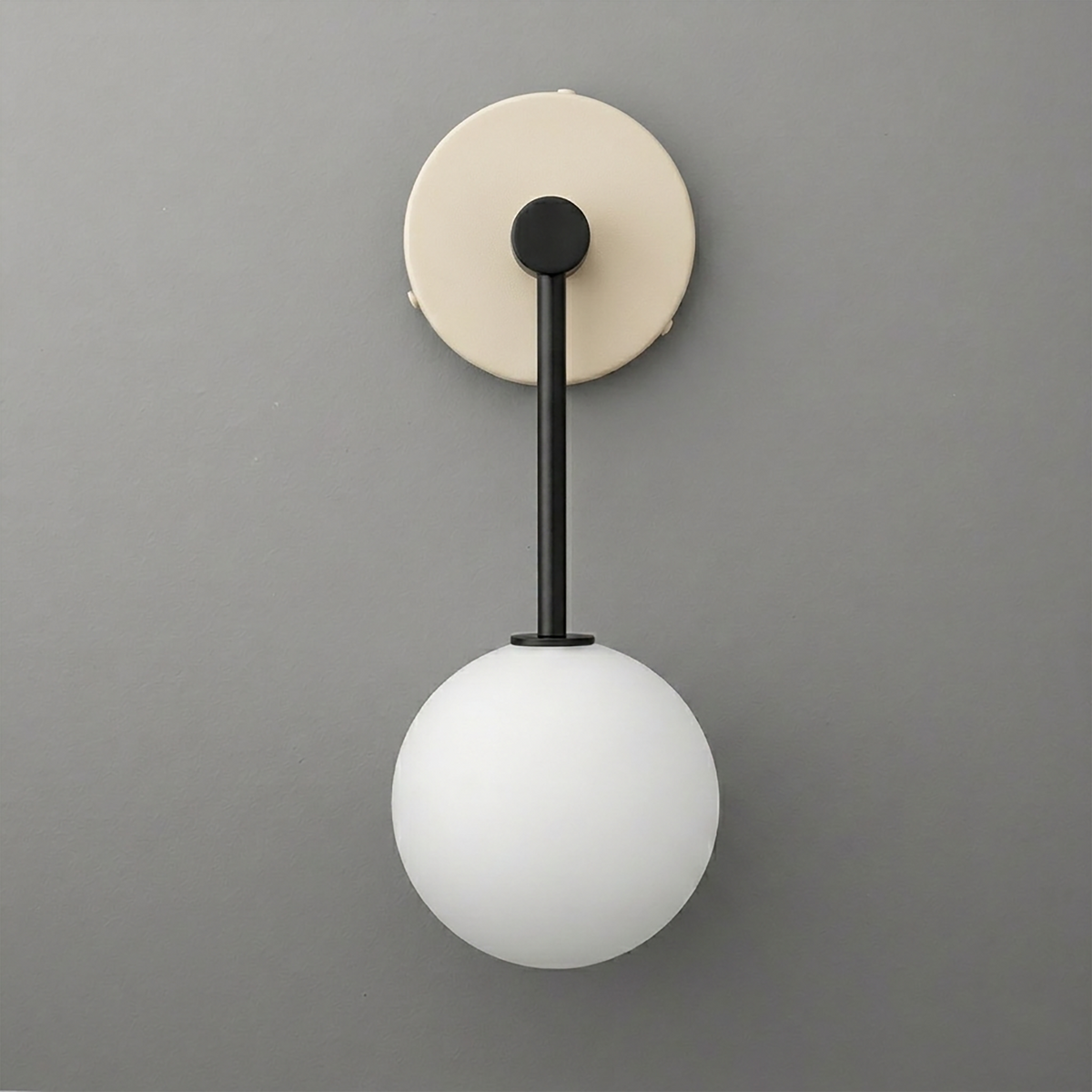Wall sconce with matte black metal rod and frosted white glass globe shade on beige circular mount. - Sconce Model No. 5999