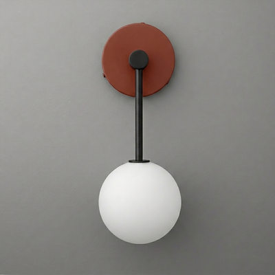 Minimalist wall sconce with a matte black rod, rust-colored round base, and a frosted white globe light. - Sconce Model No. 5999