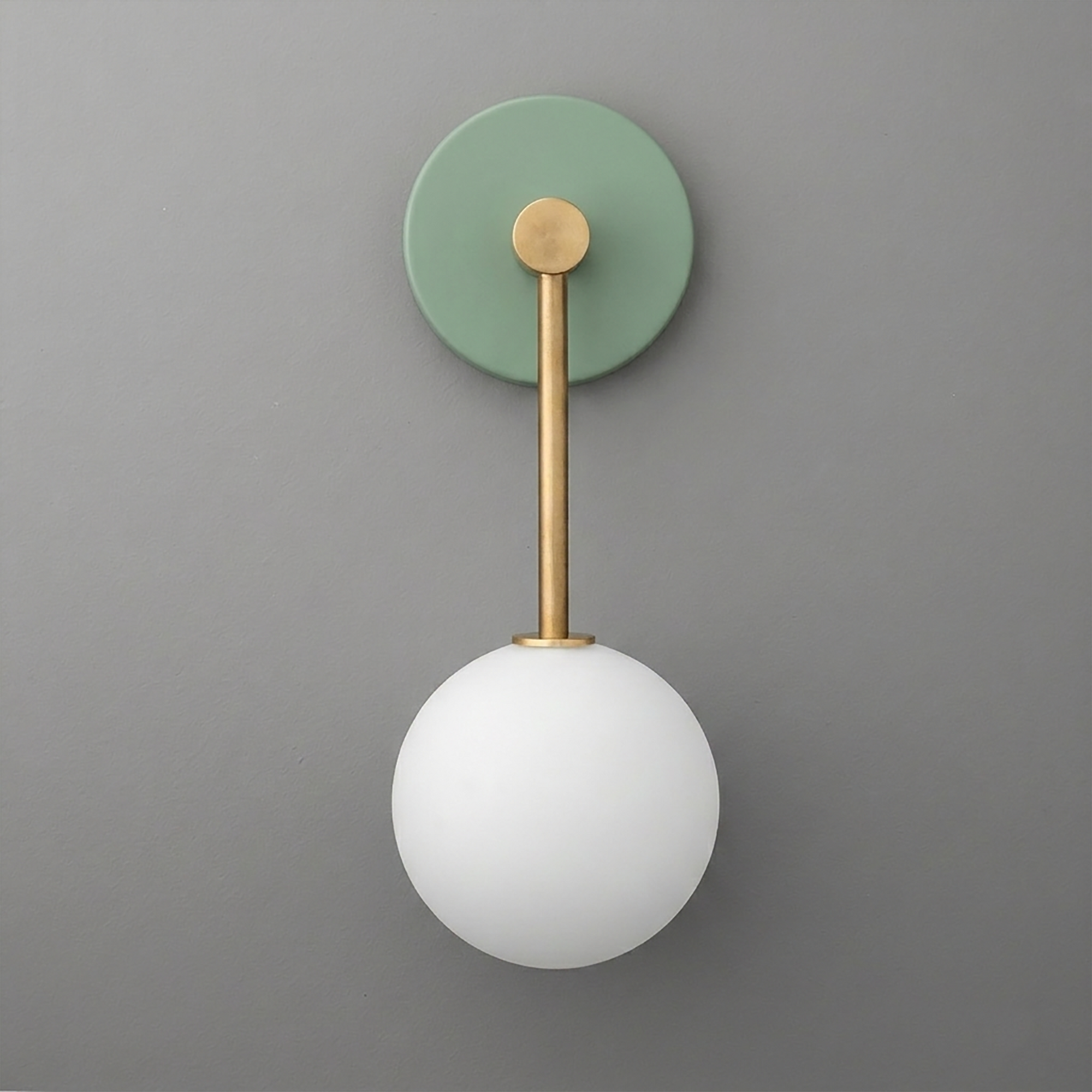 Minimalist wall sconce with matte green circular backplate, brass rod, and white frosted glass globe shade. - Sconce Model No. 5999