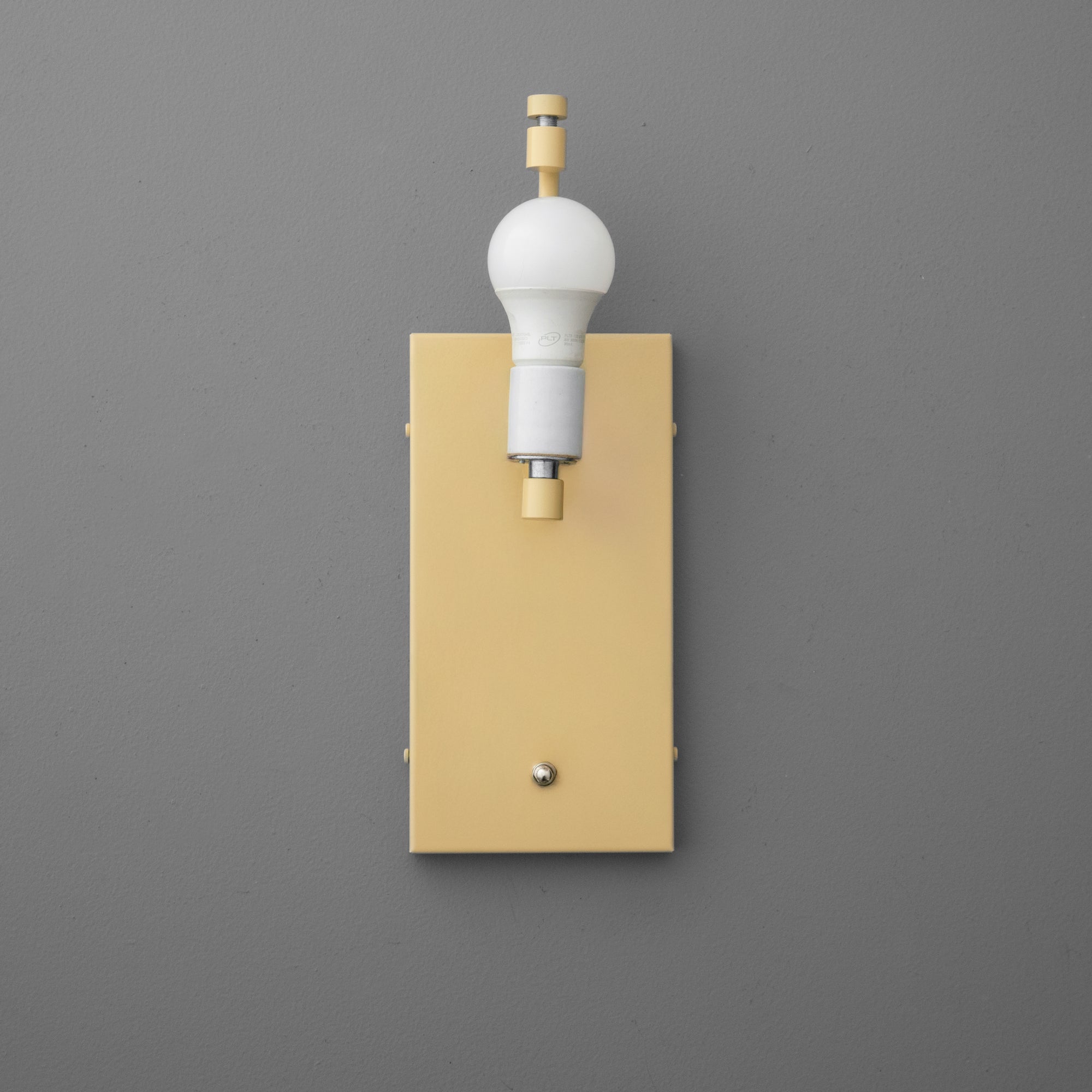 Yellow rectangular wall sconce with brass rotary switch and white bulb socket against gray background. - SCONCE MODEL NO. 7769