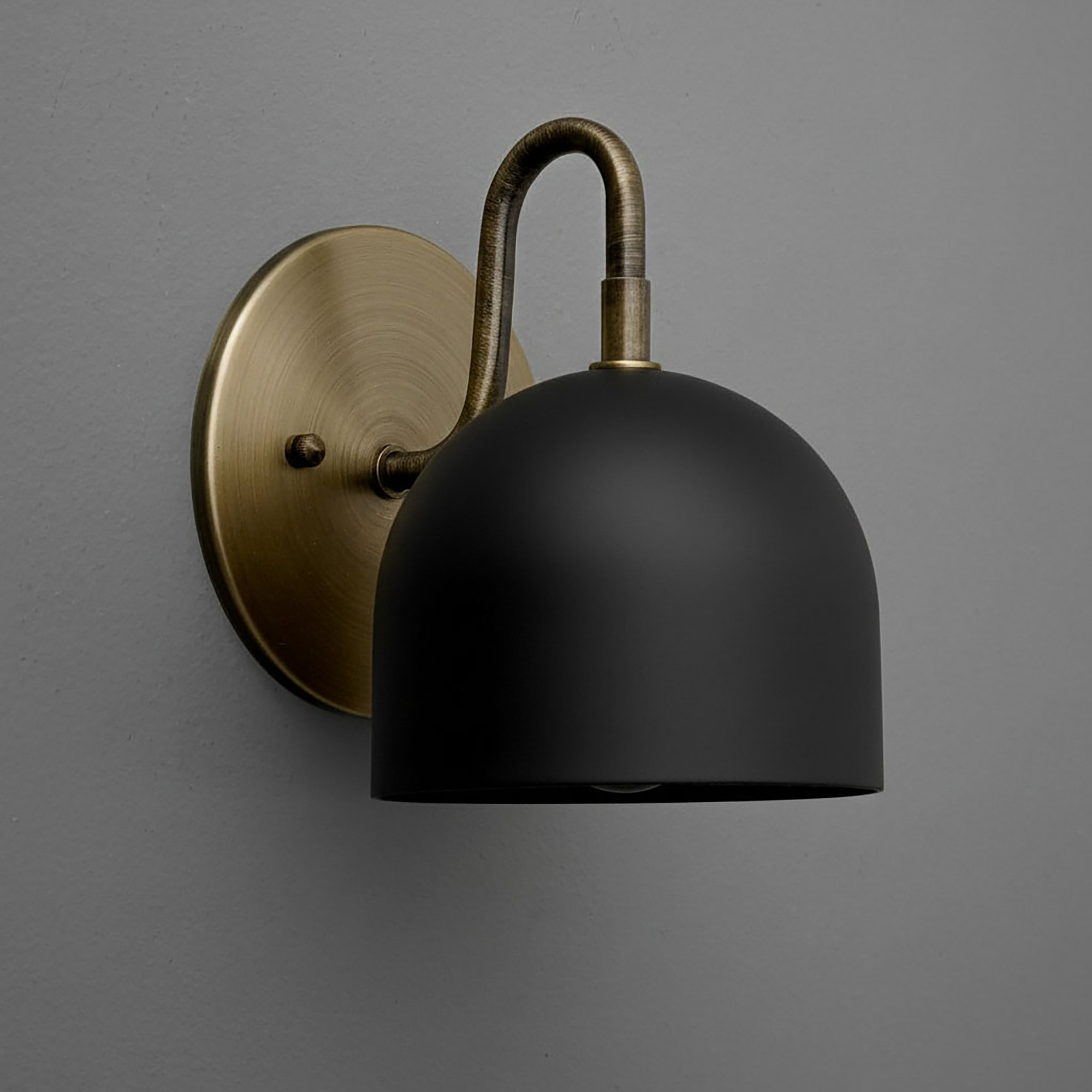 Matte black dome-shaped sconce with antique brass curved arm and round wall mount. - Sconce Model No. 5416
