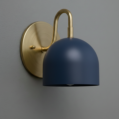 Matte navy blue dome sconce with antique brass curved arm and round wall plate on gray wall. - Sconce Model No. 5416