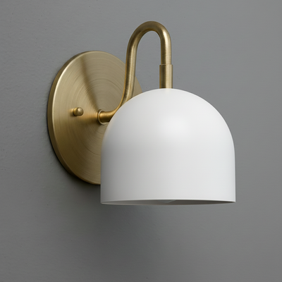 Brushed brass wall sconce with curved arm and matte white dome-shaped shade against gray wall. - Sconce Model No. 5416