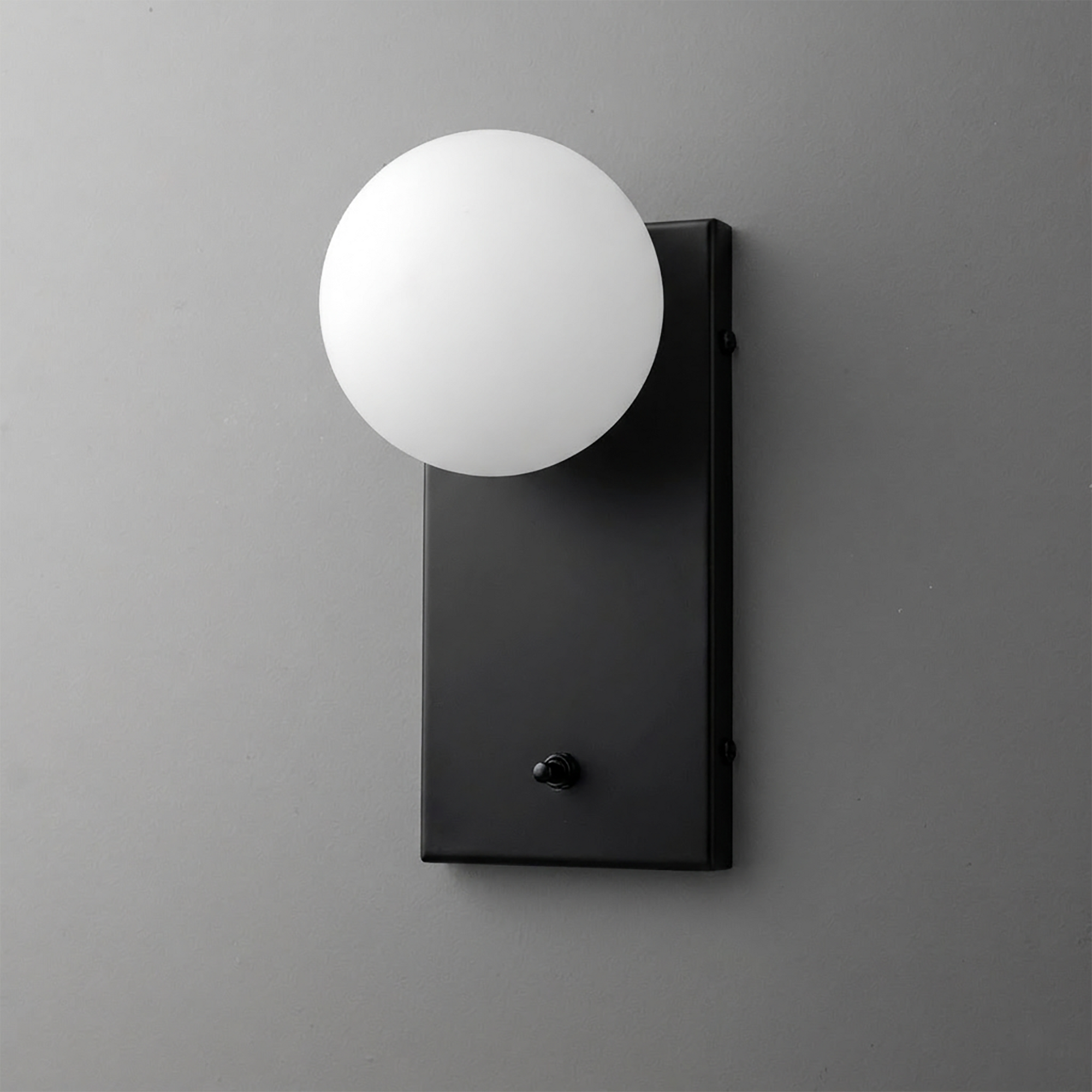 Black rectangular metal sconce with a matte finish holding a frosted white globe bulb on top. - Sconce Model No. 2196