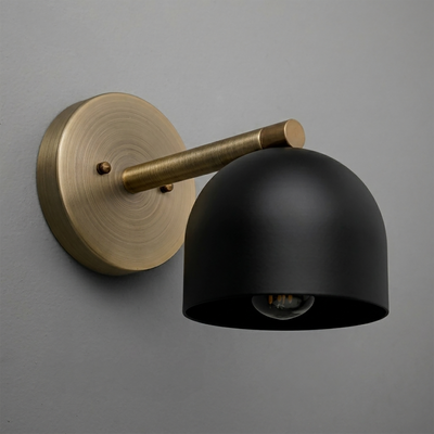 Black dome-shaped metal sconce with antique brass round mount and arm on gray wall. - Sconce Model No. 5356