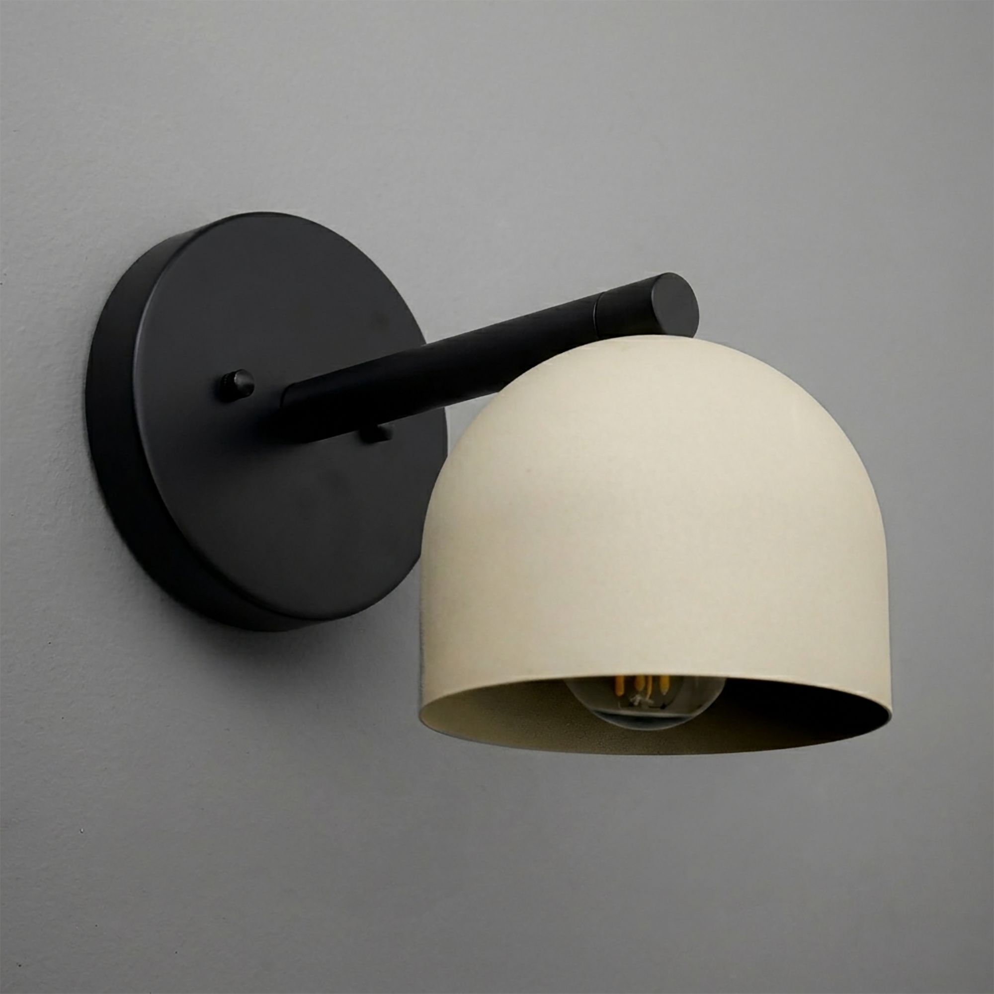 Matte black metal wall sconce with a smooth, dome-shaped cream lampshade and exposed bulb design. - Sconce Model No. 5356