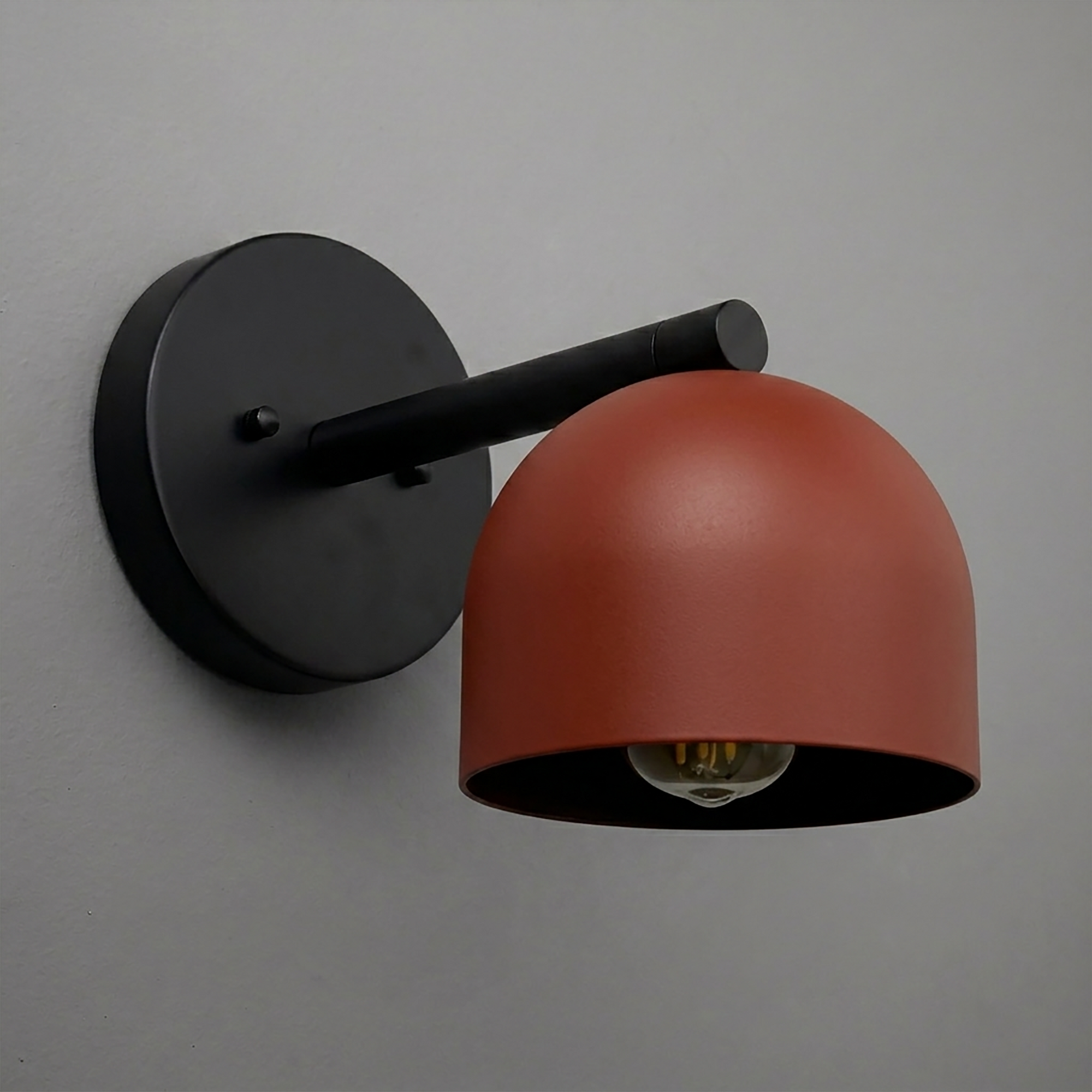 Matte black metal wall sconce with a rust-red dome-shaped shade and exposed bulb, modern design. - Sconce Model No. 5356