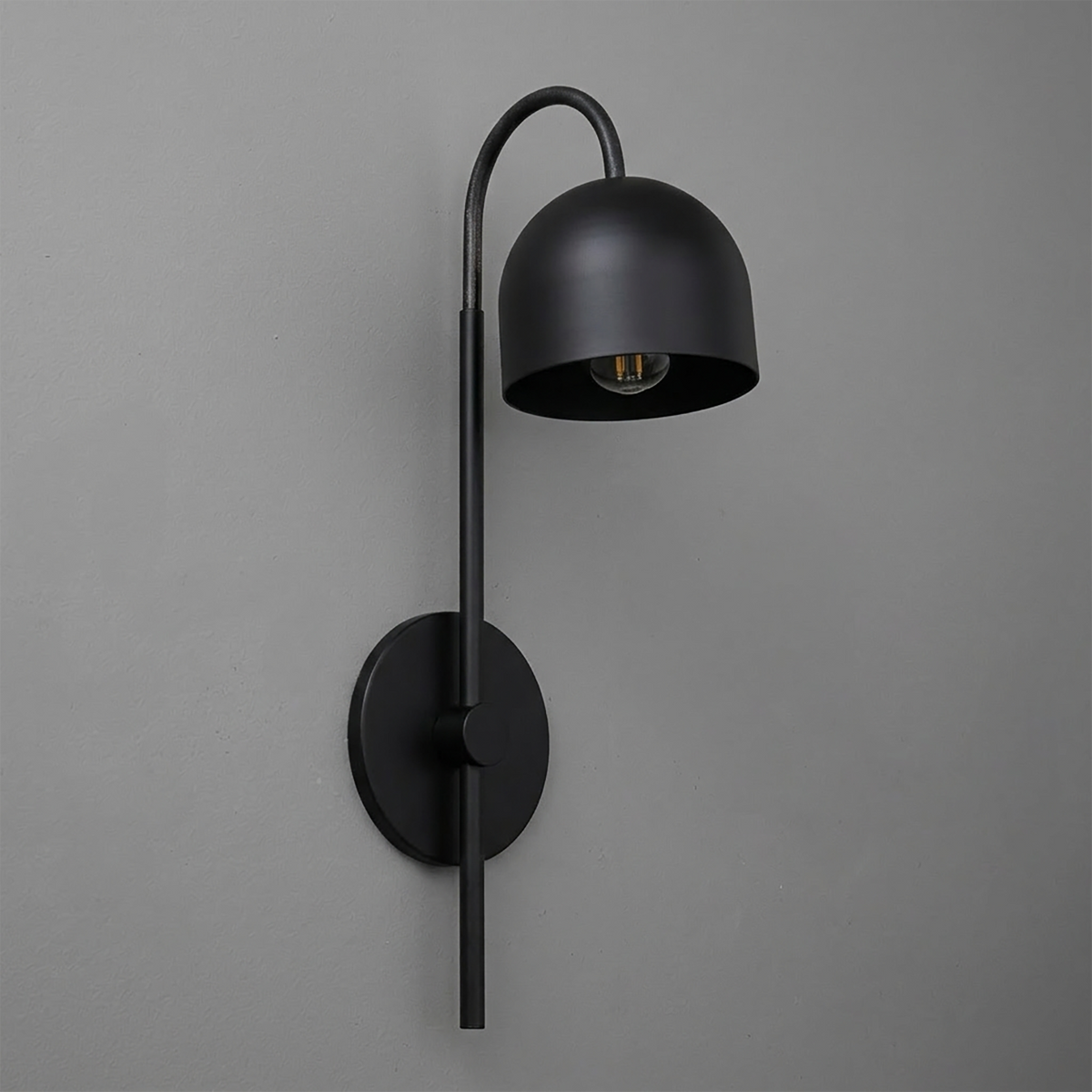 Matte black metal wall sconce with curved arm and dome-shaped shade, single bulb design. - Sconce Model No. 7340