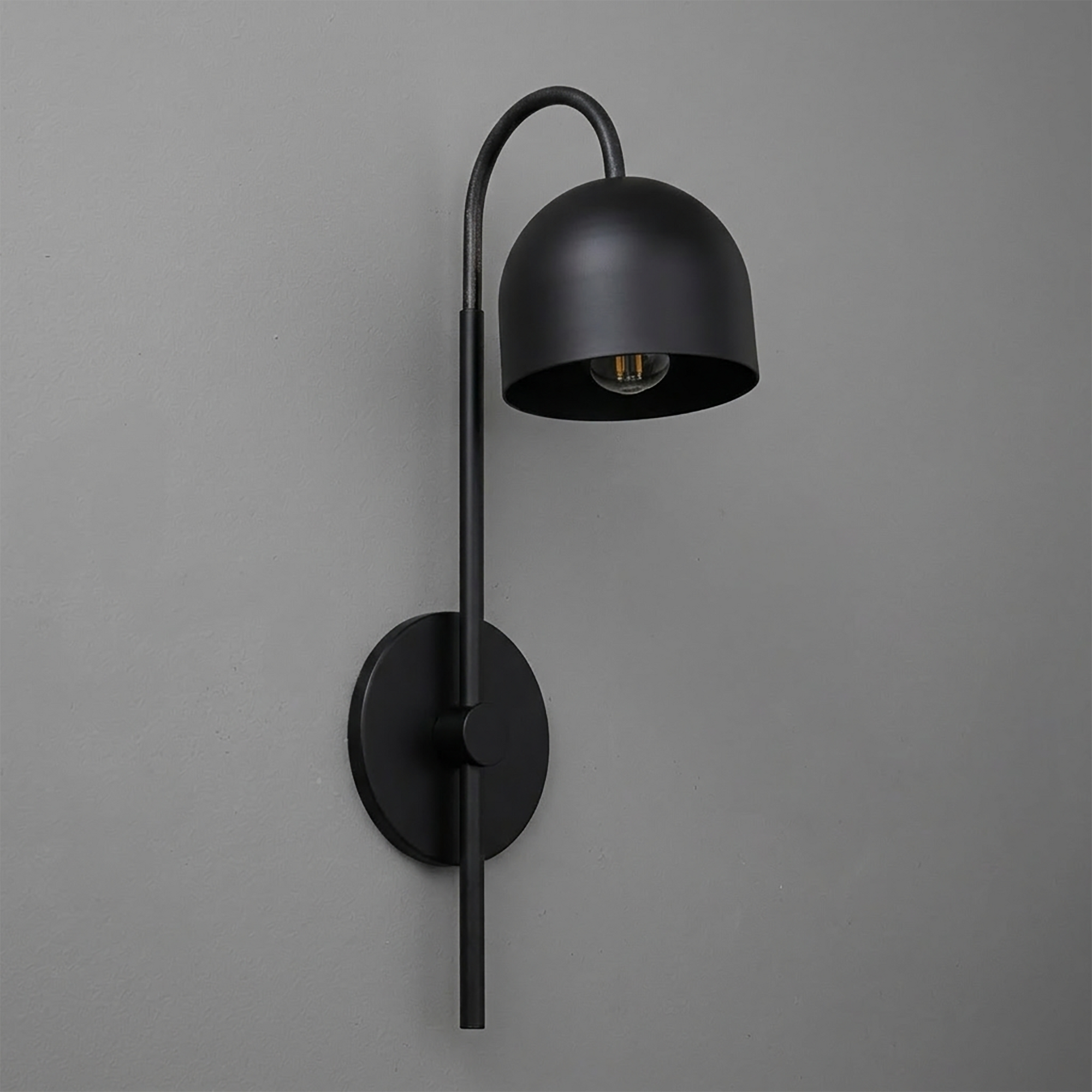 Matte black metal wall sconce with curved arm and dome-shaped shade, single bulb design. - Sconce Model No. 7340