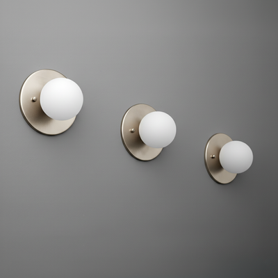 Brushed nickel sconce with frosted white 3-inch globe on round backplate, mounted on gray wall. - Sconce Model No. 5206