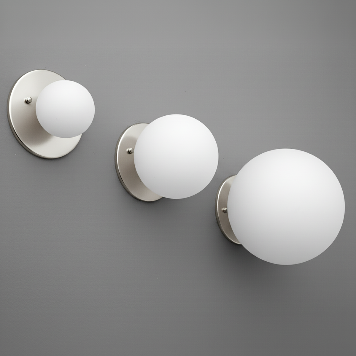 Set of three polished nickel wall sconces with frosted white glass globes in 3, 5, and 8 inch sizes. - Sconce Model No. 5206