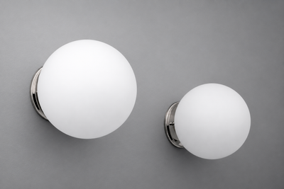 Two spherical white frosted glass wall sconces with polished chrome circular bases, one larger than the other, mounted on. - Sconce Model No. 5206