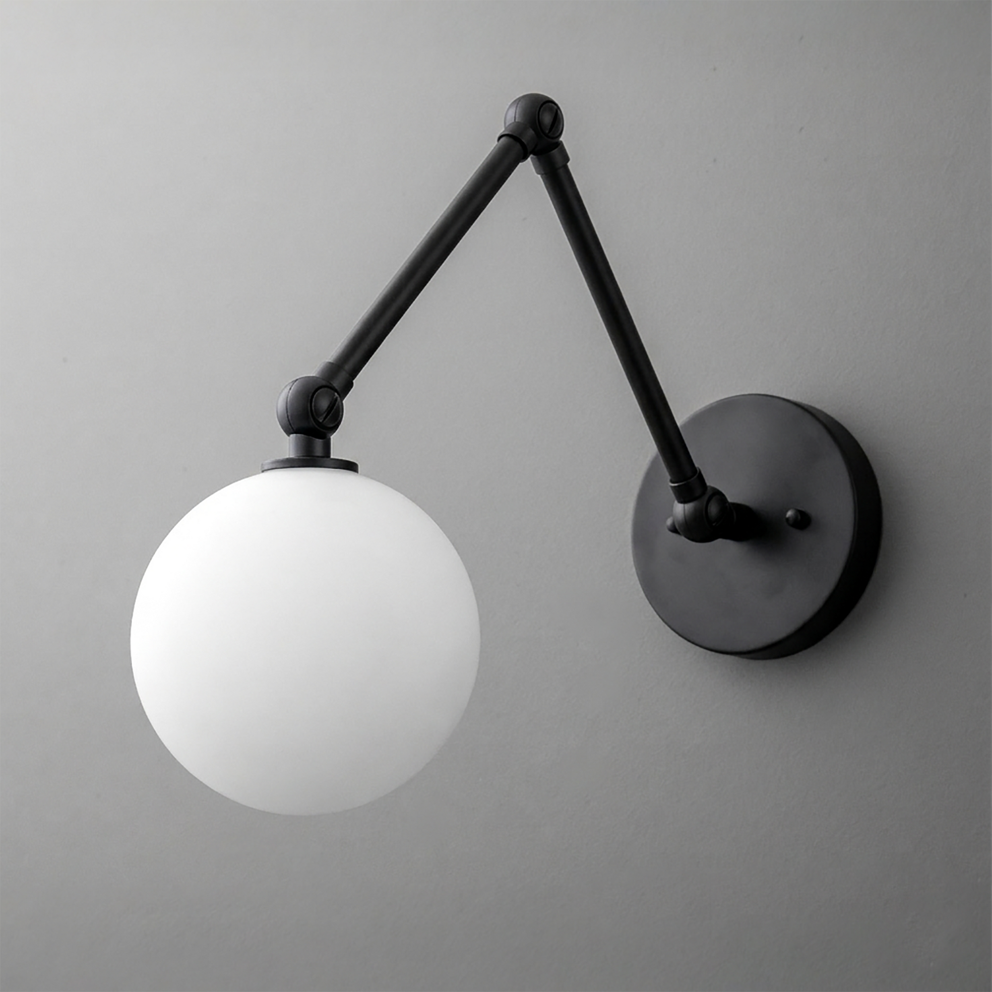 Black metal adjustable arm wall sconce with a white frosted globe shade and round wall mount. - SCONCE MODEL NO. 5202