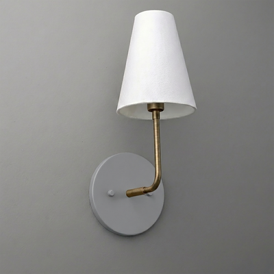 Wall-mounted sconce with round gray base, curved brass arm, and white tapered fabric shade. - SCONCE MODEL NO. 3928