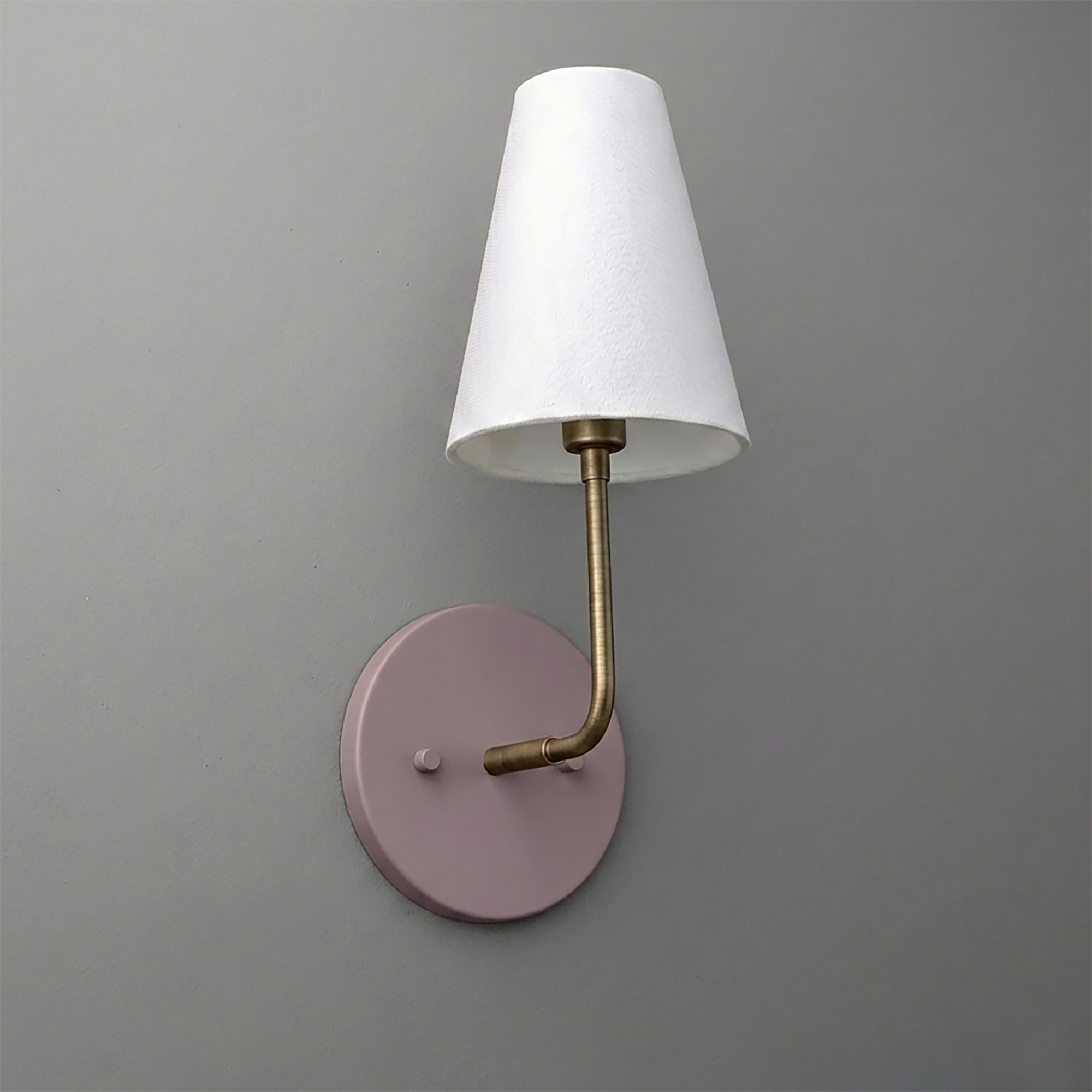 Wall sconce with round matte pink base, brass arm, and white tapered fabric shade. - SCONCE MODEL NO. 3928