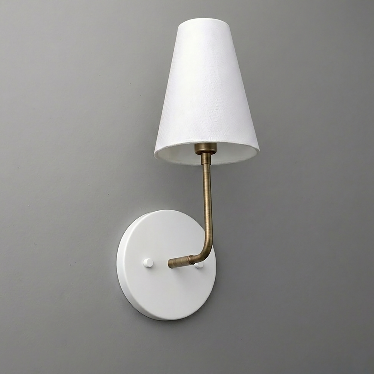 White round wall sconce with brass curved arm and white tapered fabric shade. - SCONCE MODEL NO. 3928